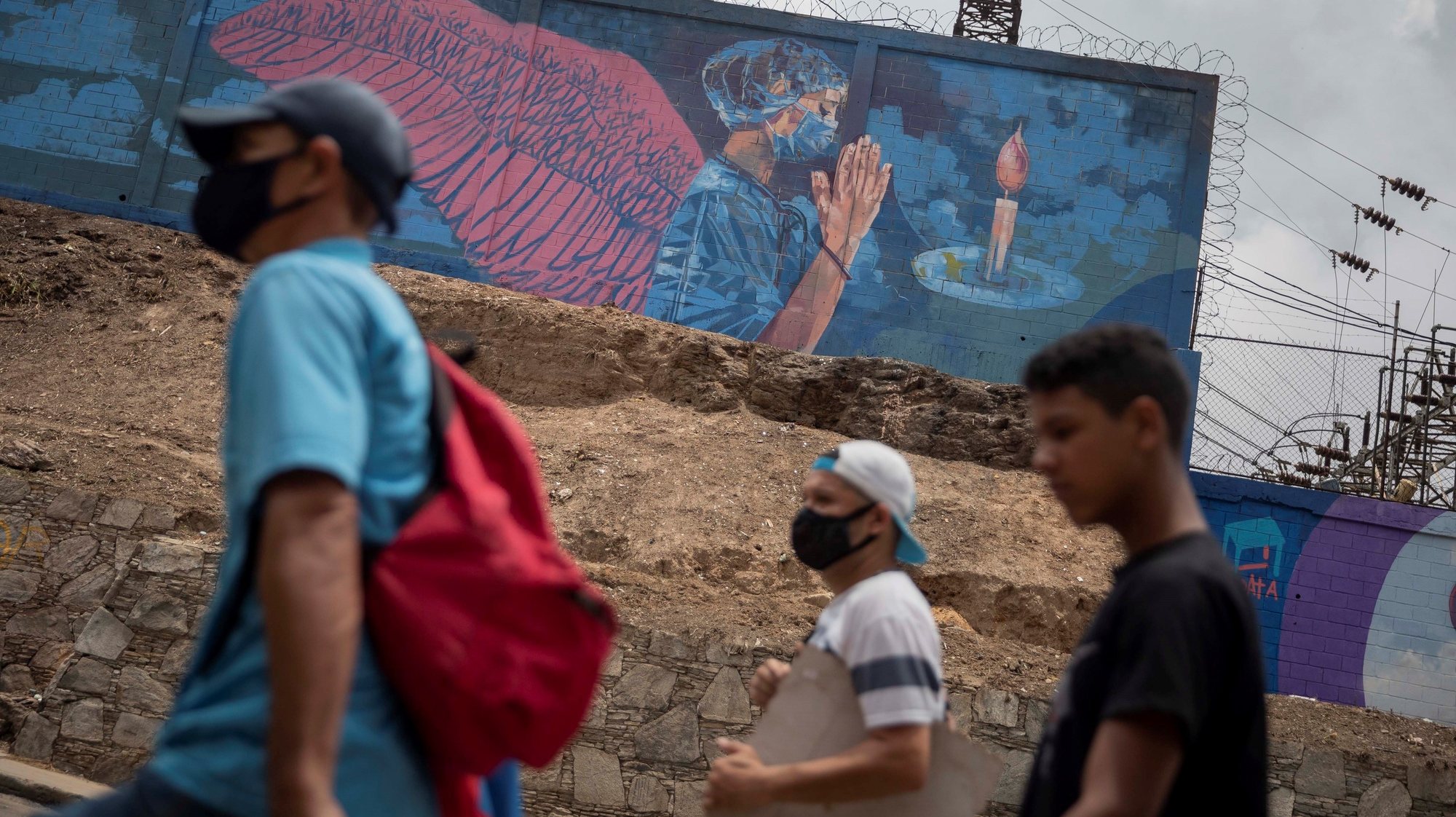 epa09173116 People walk in front of a mural showing a nurse praying in Caracas, Venezuela, 01 May 2021. A total of 19 people died in Venezuela in the last 24 hours from COVID-19, bringing the total number of deaths since the pandemic began to 2,155, the Minister of Communication, Freddy Nanez, reported this Saturday.  EPA/RAYNER PENA
