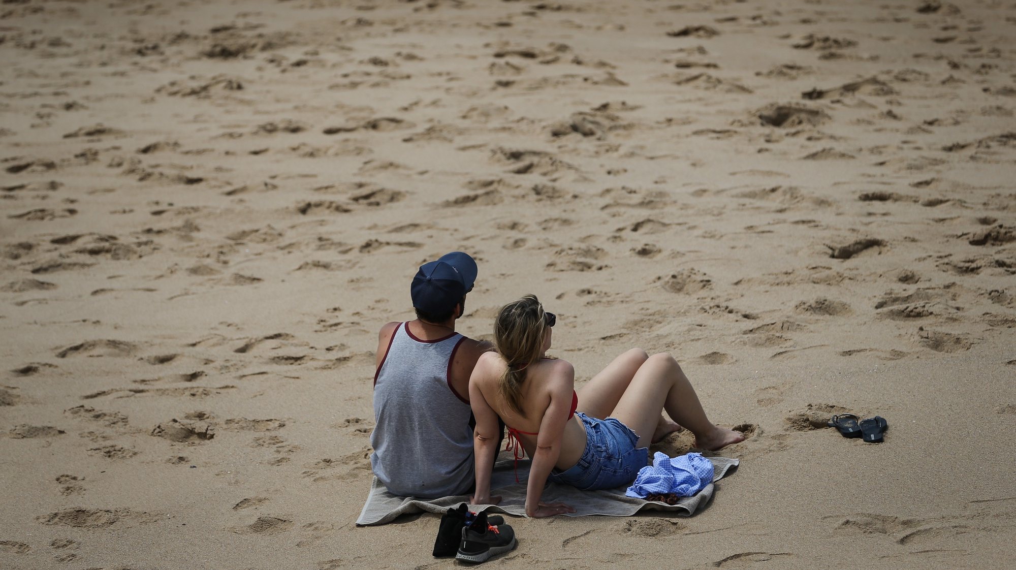 Um casal apanha sol no dia em que se assinala a abertura da época balnear na praia de São Pedro do Estoril, em Cascais, 15 de maio de 2021.  RODRIGO ANTUNES/LUSA