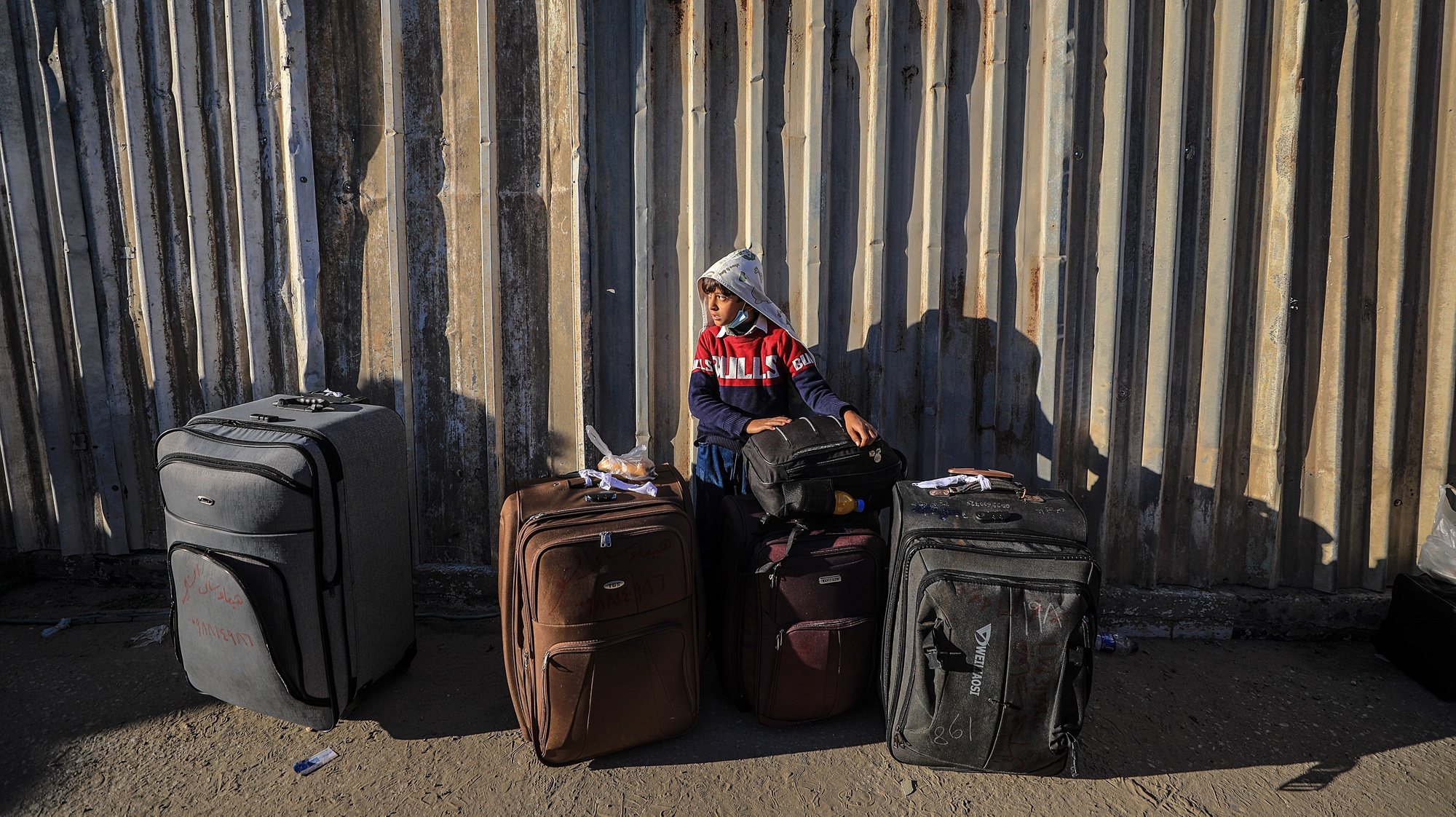 epa08980244 A Palestinian boy waits with his family to cross into Egypt through the Rafah border crossing between Gaza Strip and Egypt after its closure from March 2020 as a precautionary measure against the spread of the coronavirus disease (COVID-19) pandemic, in Rafah, southern Gaza Strip, 01 February 2020. Egyptian Authorities reopened Rafah crossing for four days for the Fifth time since March 2020 for humanitarian cases, including the allowance of crossing the border for people needing medical treatment unavailable in Gaza as well as students enrolled at Egyptian universities and Gazans with jobs abroad.  EPA/MOHAMMED SABER