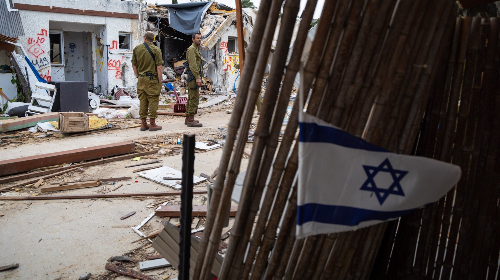epa10989455 Israeli soldiers stand near damaged homes during a press visit at Kfar Aza Kibbutz, southern Israel, 22 November 2023. The kibbutz, located near the Gaza border, was the scene of an Hamas attack on 07 October which resulted in the deaths of dozens of Israelis. More than 12,700 Palestinians and at least 1,200 Israelis have been killed, according to the Israel Defense Forces (IDF) and the Palestinian health authority, since Hamas militants launched an attack against Israel from the Gaza Strip on 07 October, and the Israeli operations in Gaza and the West Bank which followed it.  EPA/CHRISTOPHE PETIT TESSON
