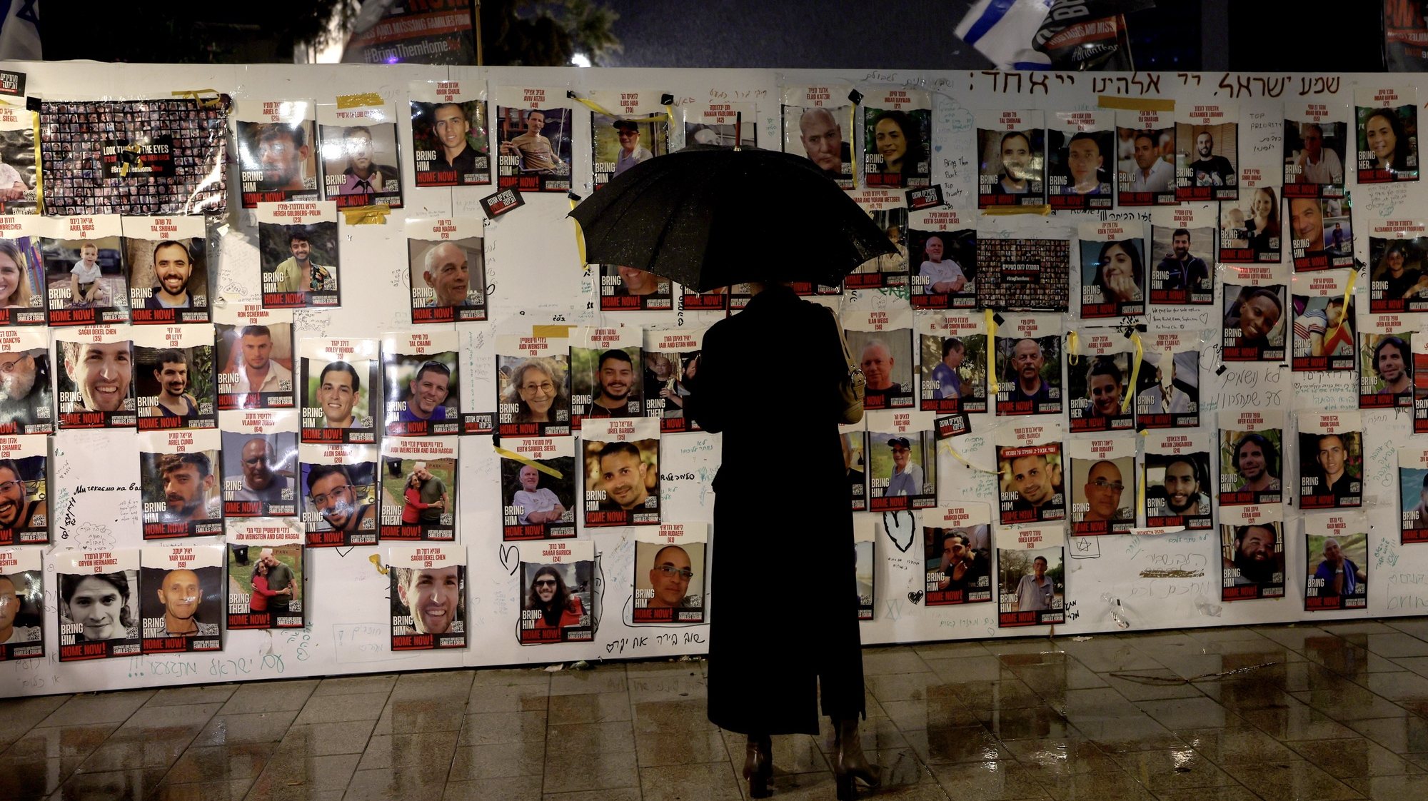 epa11042426 An Israeli activist looks at pictures of hostages held by Hamas in Gaza Strip, at the Hostages Square, in Tel Aviv, Israel, 23 December 2023. Thousands of Israelis and Palestinians have died since the militant group Hamas launched an unprecedented attack on Israel from the Gaza Strip on 07 October, and the Israeli strikes on the Palestinian enclave which followed it.  EPA/ATEF SAFADI