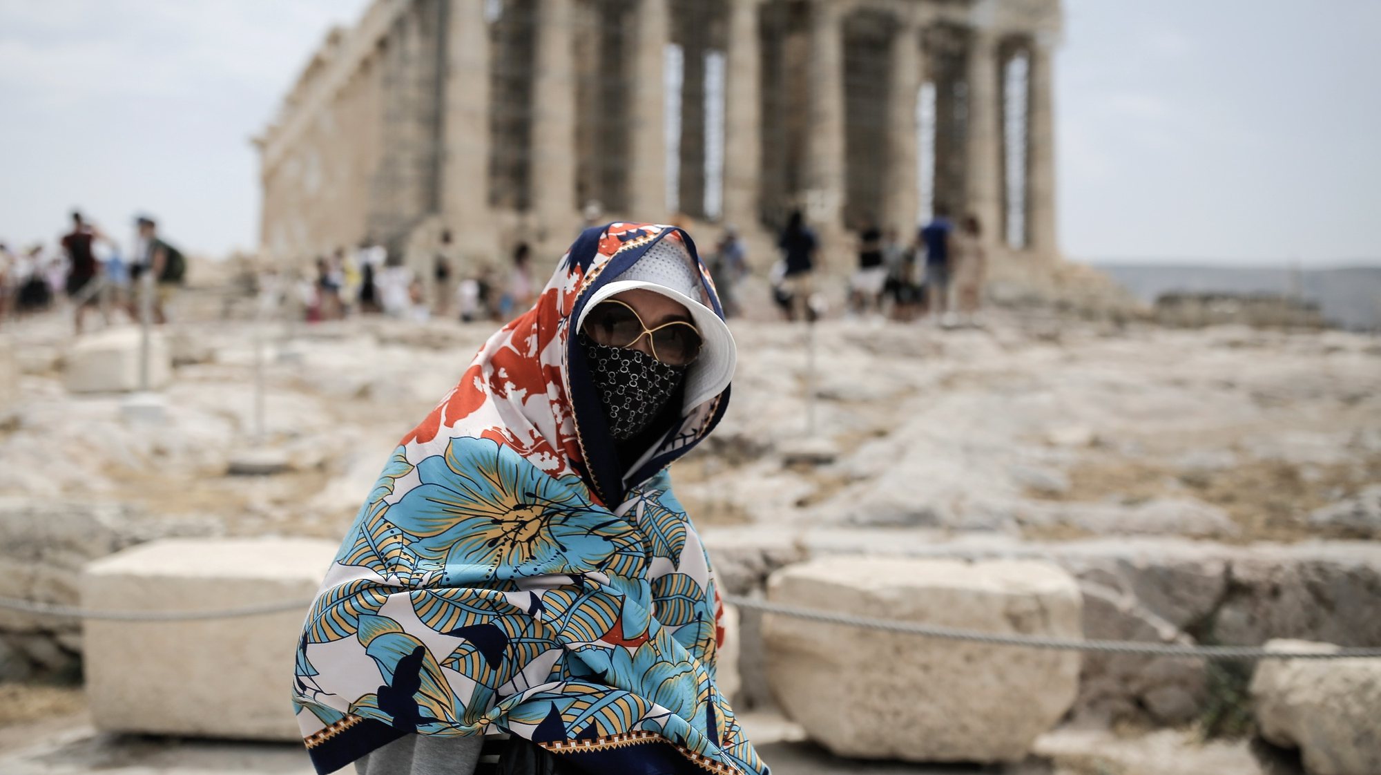 epa11403649 A visitor wearing a hat and a scarf to shield her from the sun walks in front of the Parthenon temple atop the Acropolis hill during a heatwave, in Athens, Greece, 11 June 2024. The extended high pressure area over the coasts of Africa and central Mediterranean, which is accompanied by very warm air masses, is gradually extending eastward and will bring very high temperatures in Greece from 11 until 14 June. A circular of the Interior Ministry outlines how civil services will operate during the heatwave forecast in Greece by the National Meteorological Service.  EPA/KOSTAS TSIRONIS