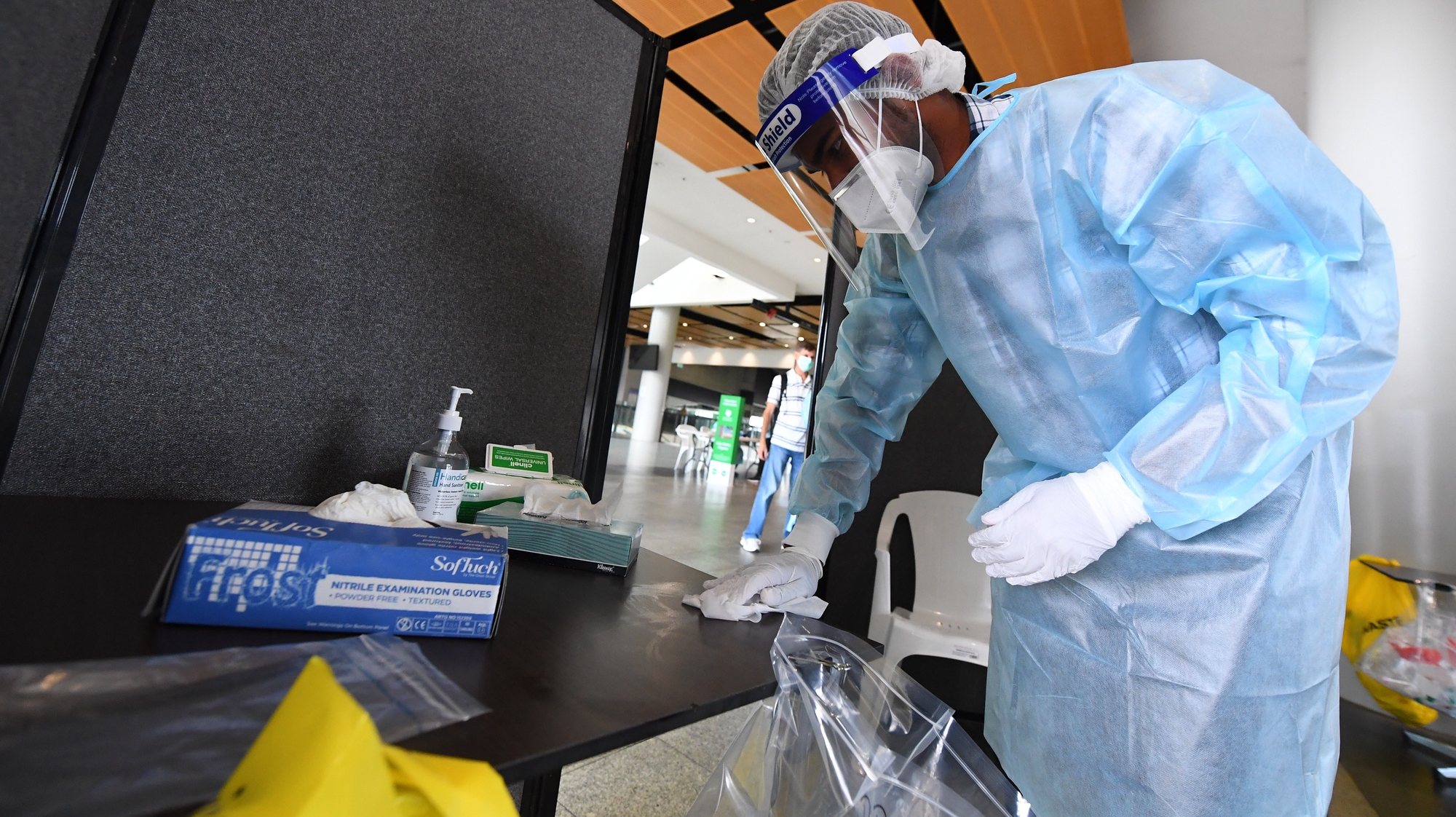epa08921385 A healthcare worker sanitizes a table at a coronavirus testing facility at the MCG stadium in Melbourne, Australia, 06 January 2021. The MCG has been listed as a potential location for a recent cluster of COVID-19 infections after a man attended day two of the Boxing Day Test and later tested positive to coronavirus.  EPA/JAMES ROSS AUSTRALIA AND NEW ZEALAND OUT