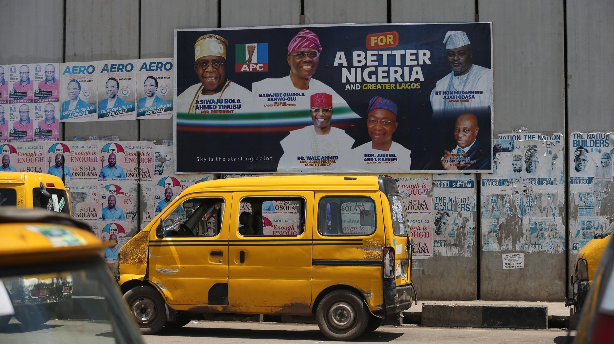 epa10497119 Lagos commercial transport are parked near a billboard bearing the portrait photos of Nigeria&#039;s President-elect Bola Ahmed Tinubu (L) and other contestants in Agege district of Lagos, Nigeria 01 March 2023.  EPA/Akintunde Akinleye