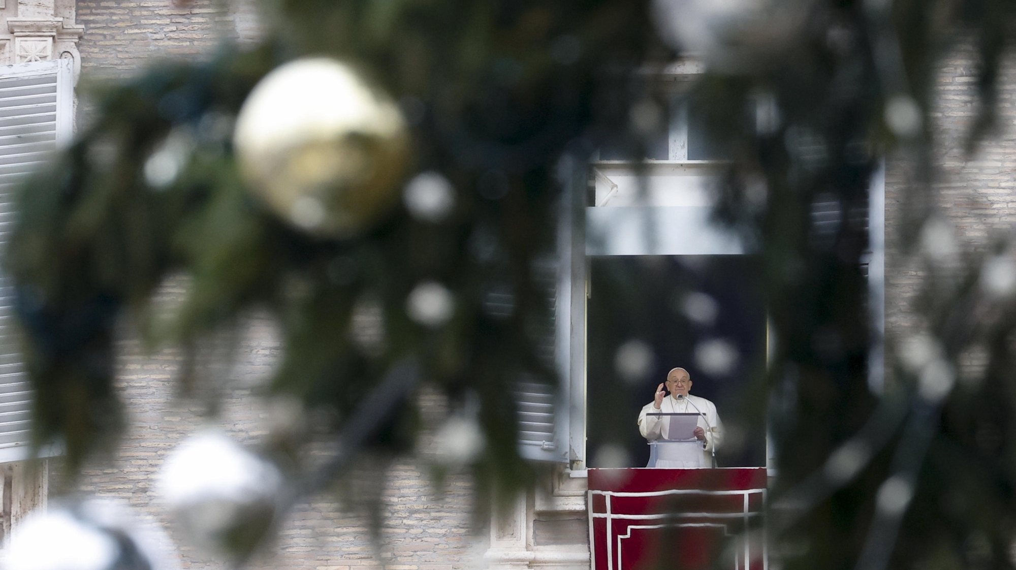 epa11042913 Pope Francis seen through Christmas tree balls as he leads the Angelus prayer from the window of his office overlooking Saint Peter&#039;s Square, Vatican City, 24 December 2023.  EPA/FABIO FRUSTACI