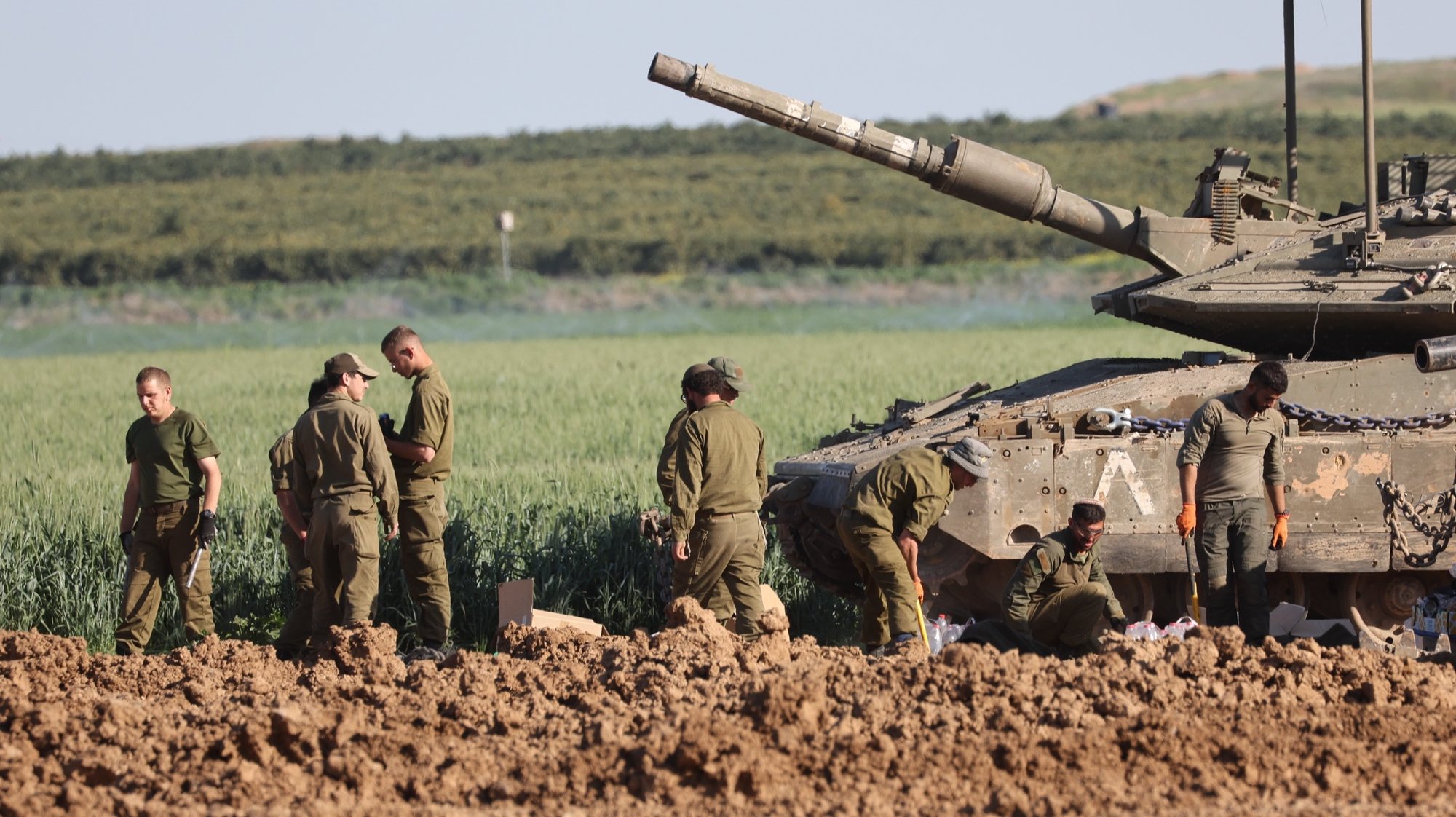 epa11211358 Israeli soldiers stand next to a tank near the border fence with the Gaza Strip, as seen from the Israeli side in southern Israel, 10 March 2024. More than 31,000 Palestinians and over 1,300 Israelis have been killed, according to the Palestinian Health Ministry and the Israel Defense Forces (IDF), since Hamas militants launched an attack against Israel from the Gaza Strip on 07 October 2023, and the Israeli operations in Gaza and the West Bank which followed it.  EPA/ABIR SULTAN