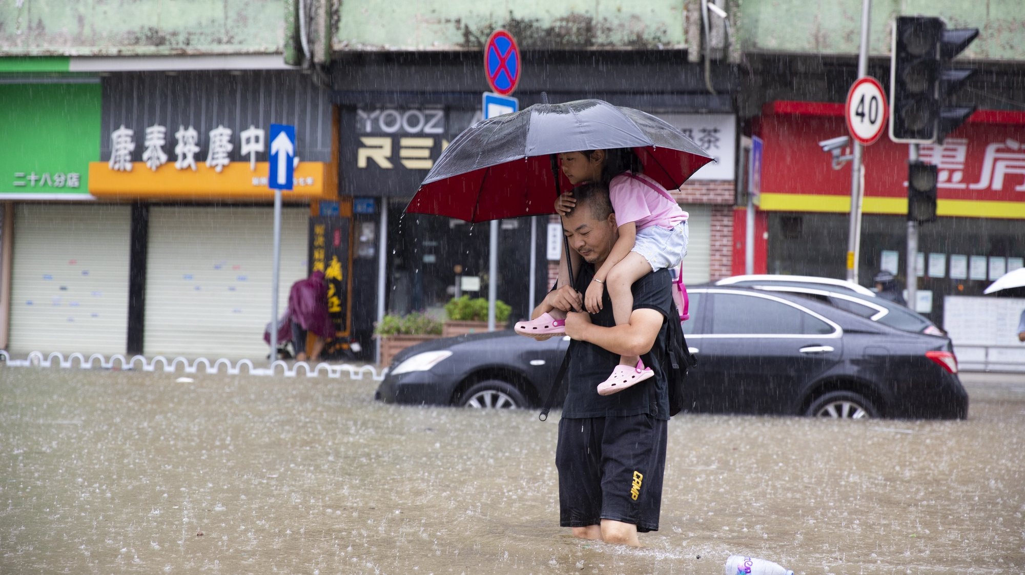 epa10848869 A man carrying his child wades through floodwater on a flooded road in Panyu District of Guangzhou, south China&#039;s Guangdong Province, 08 September 2023. Affected by the residual cloud system outside Typhoon Haikui and the monsoon, many cities and counties in the Pearl River Delta region have experienced torrential rains.  EPA/XINHUA / Li Jiale CHINA OUT / UK AND IRELAND OUT  /       MANDATORY CREDIT  EDITORIAL USE ONLY