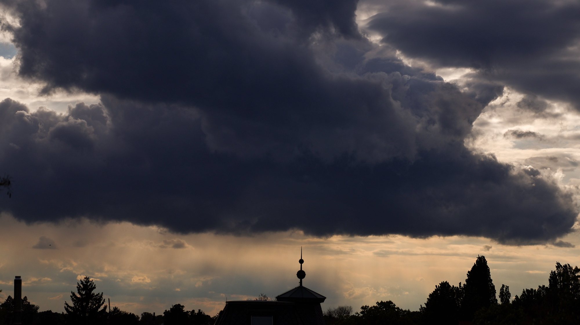 epa11292278 Dark clouds form over the rooftop of a residential house during a rainy evening in Berlin, Germany, 21 April 2024. Meteorologists predict rainy weather with temperatures around 07 degrees Celsius in the next few days in the German capital.  EPA/FILIP SINGER
