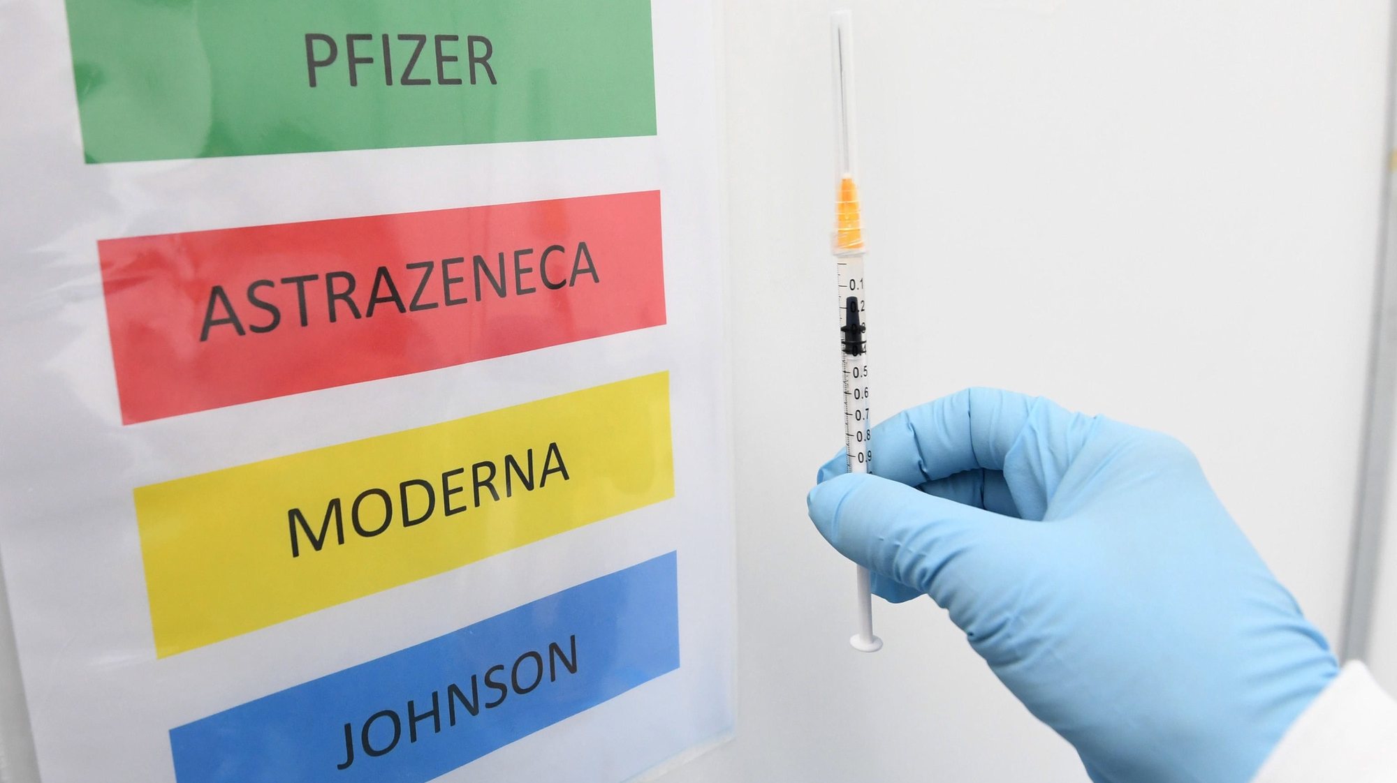 epa09170062 A medical staff holds a syringe next to a color code sign listing the Covid-19 vaccines BioNTech/Pfizer, AstraZeneca, Moderna and Johnson&amp;Johnson at the Covid-19 vaccination hub set up in Novegro, near Milan, Italy, 30 April 2021.  EPA/Daniel Dal Zennaro