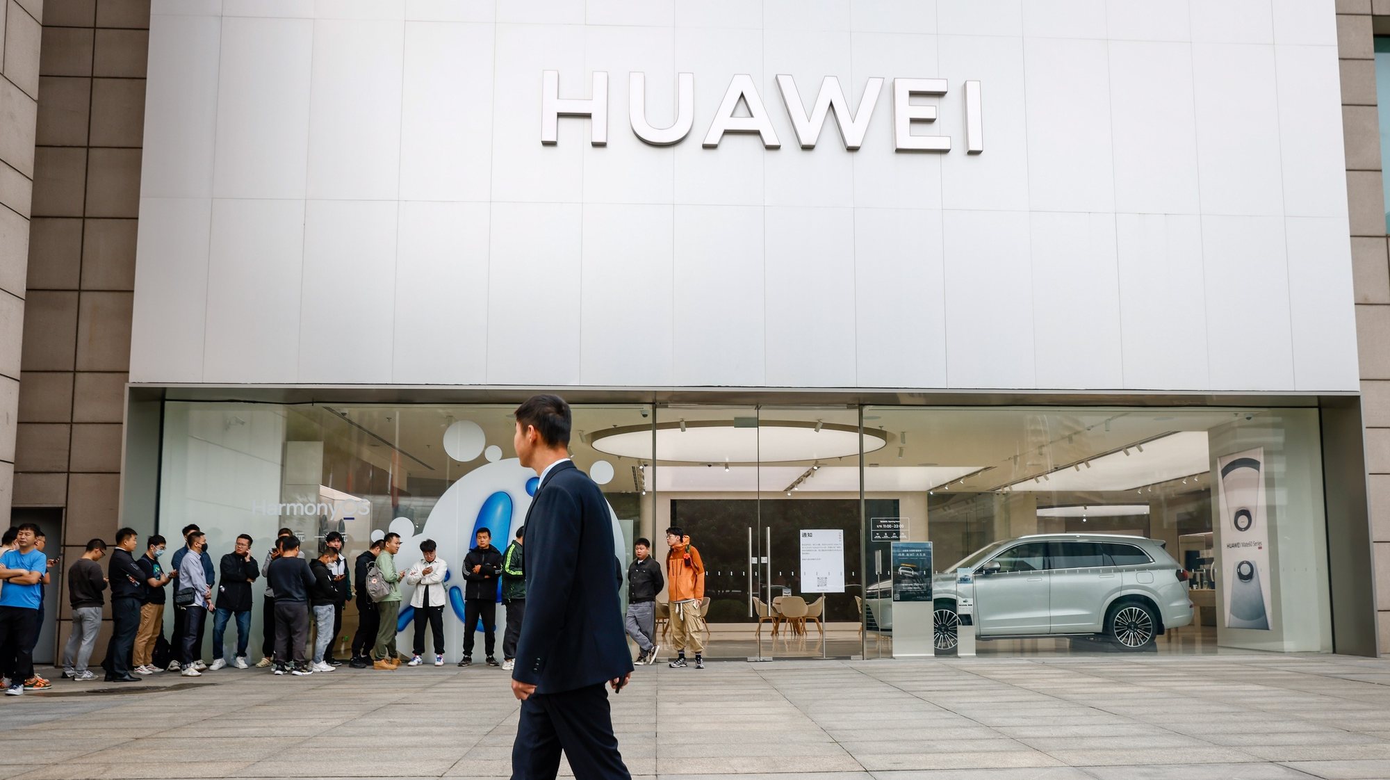 epa10881888 A security person patrols as people lineup outside a Huawei store in Beijing, China, 25 September 2023. Huawei launched its new line of Mate 60 models which are the Mate 60, Mate 60 Pro, Mate 60 Pro+ and Mate 60 Ultimate Design.  EPA/MARK R. CRISTINO