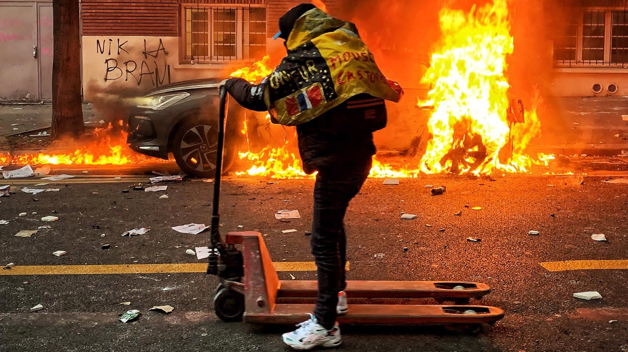 epa08864234 A protester moves on a hand lift truck as a car is on fire during a protest against France&#039;s controversial global security law, in a street between Porte des Lilas and Gambetta square, in Paris, France, 05 December 2020. The global security legislation passed by the French Parliament aims to ban the distribution of photos in which police officers and gendarmes can be identified in a way which is harmful to their image.  EPA/BENJAMIN LEGIER