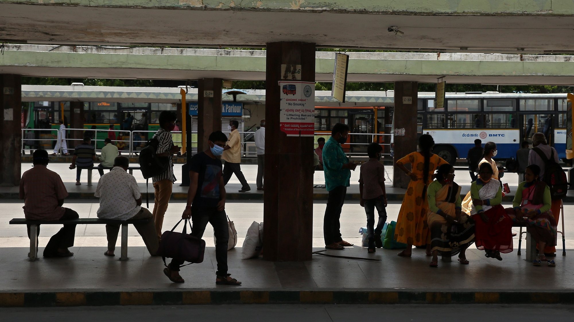 epa09290423 A general view showing people wait for buses at city bus stand, after the lockdown restrictions eased in Bangalore, India, 21 June 2021. The Karnataka State government has eased coronavirus restrictions in several districts and imposed night curfew will be in effect from 7pm to 5am in all other districts and weekend curfew will be imposed in Bangalore city.  EPA/JAGADEESH NV