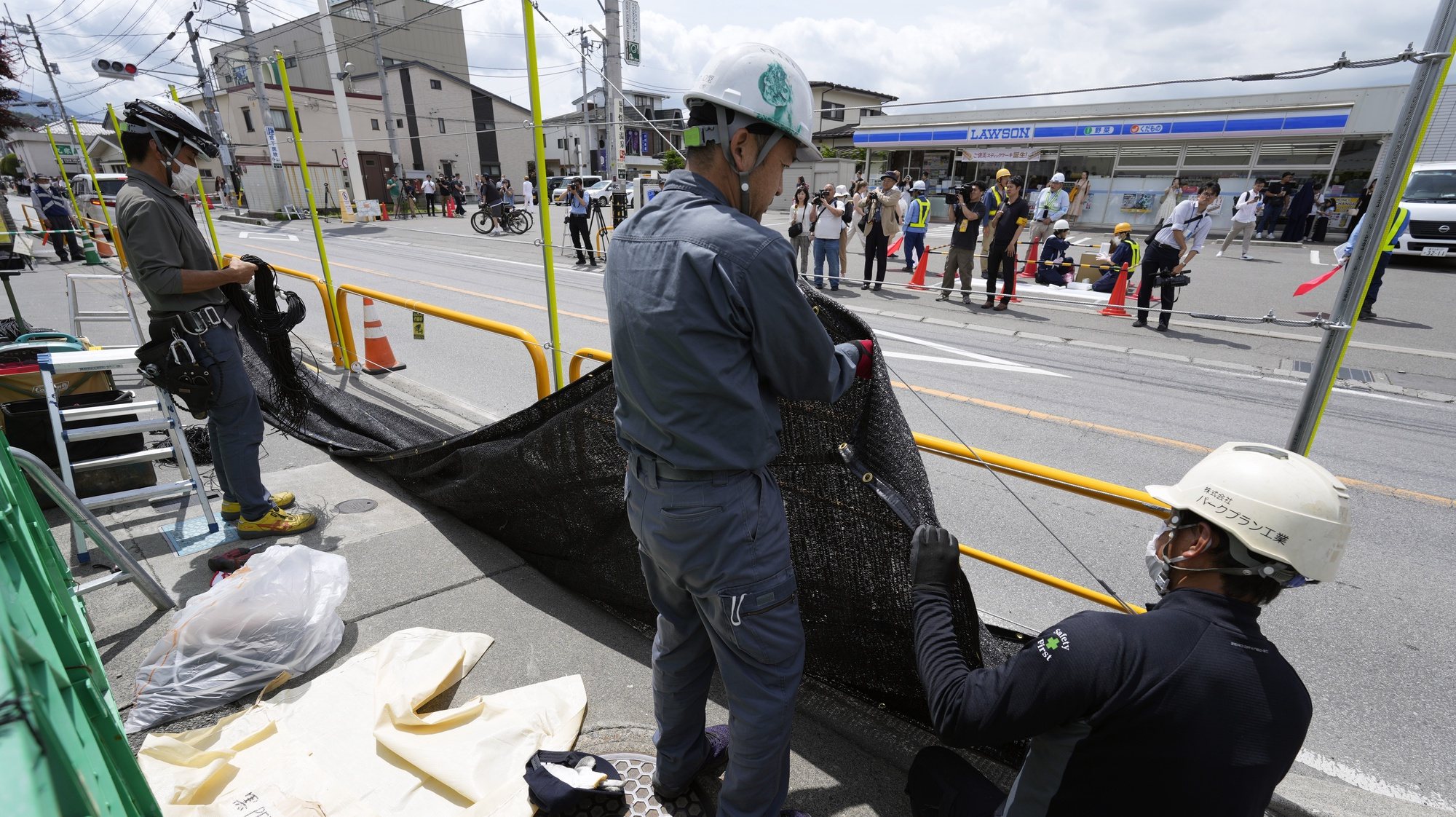 epa11356932 Workers install a black shading net on the opposite side of the Lawson Kawaguchiko Ekimae convenience store in Fujikawaguchiko, north of Mount Fuji, Japan, 21 May 2024. The town of Fujikawaguchiko, north of Mount Fuji, installed a black shading net to block the view of Japan&#039;s iconic volcano from a particular spot before the Lawson Kawaguchiko Ekimae convenience store that became popular in the last two years to deter tourists who crowd there to photograph it following complains from locals.  EPA/FRANCK ROBICHON