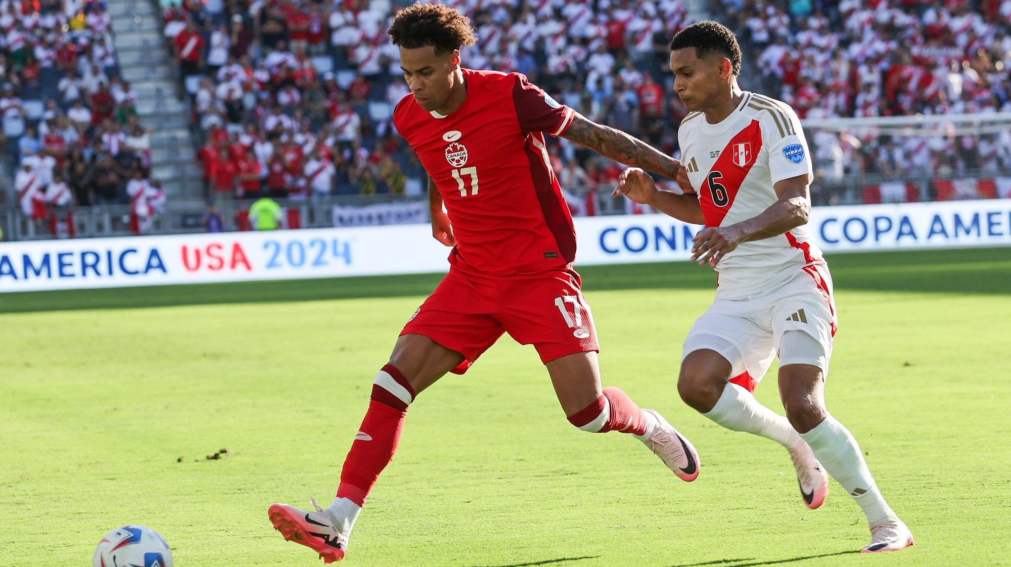 epa11438118 Canada forward Tajon Buchanan (L) and Peru defender Marcos Lopez (R) battle for the ball during the second half of the CONMEBOL Copa America 2024 group A match between Peru and Canada, in Kansas City, Kansas, USA, 25 June 2024.  EPA/WILLIAM PURNELL