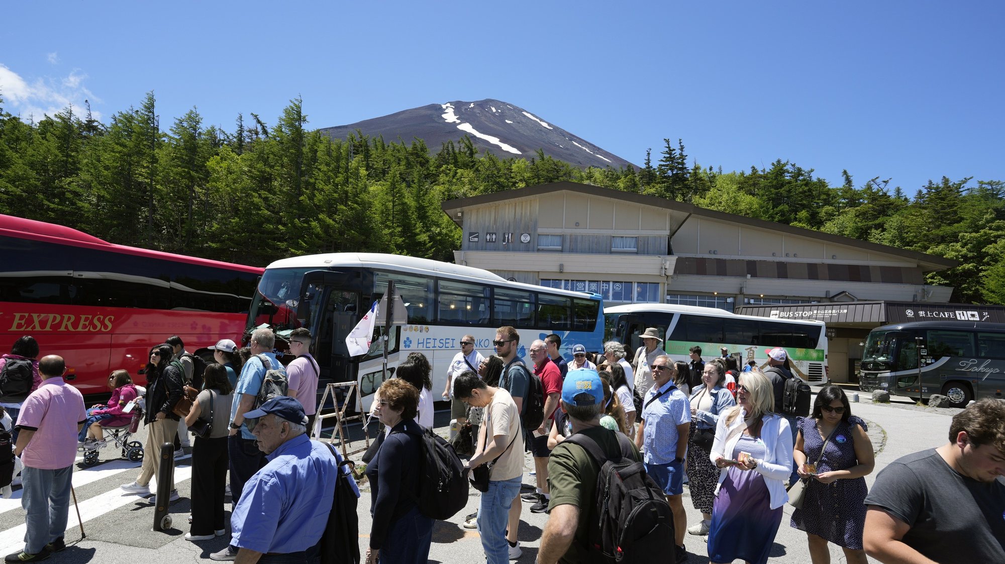 epa11421894 Tourists from abroad gather near buses at Mount Fuji 5th station as the summit is seen in the background in Yamanashi prefecture, Japan, 19 June 2024. For the first time, the prefecture will start collecting a mandatory hiking fee of 2000 yen (about 12 euros) per person and an optional &#039;donation fee&#039; of 1000 yen (6 euros) per person for climbing the Mount Fuji from the 5th station. An online reservation system started operations on 20 May 2024 ahead of the opening of the Mt. Fuji Yoshida Route on 01 July 2024. Also, access to the Yoshida Route will be limited to 4000 people per day during the hiking season from 01 July until 10 September 2024. According to data released by Japan National Tourism Organization on 19 June 2024, the number of foreign visitors traveling to Japan topped the three million mark for the third month in a row, an increase of 60 percent from the same month of 2023.  EPA/FRANCK ROBICHON