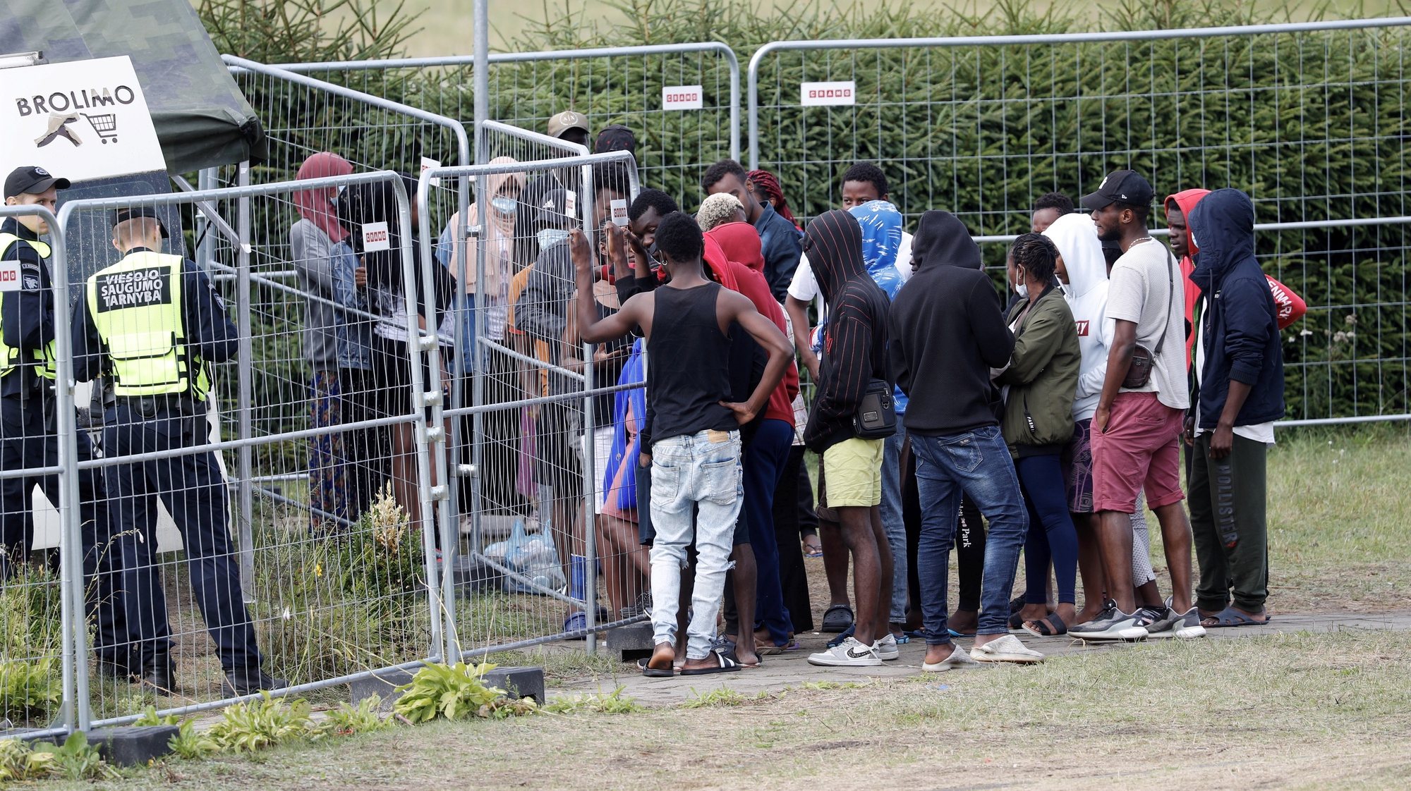 epa09388795 Detained migrants waiting in line for buying goods from an off-site store in a car at the migrant detention centre in Vydeniai, Lithuania, 02 August 2021. Some 3,800 migrants were detained in Lithuania in 2021 so far and officials have accused the Belarus regime to be behind an increased number of migrants crossing into Lithuania.  EPA/TOMS KALNINS