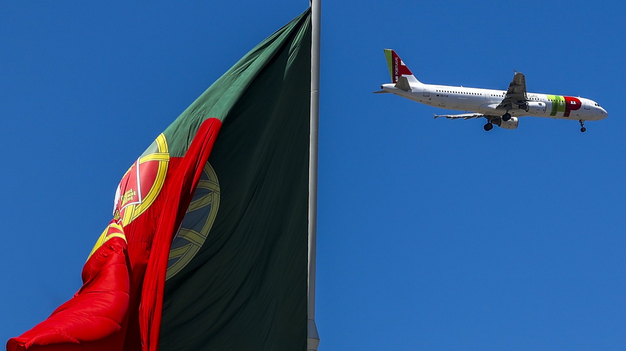 Um avião da TAP voa sobre uma bandeira de Portugal, no Parque Eduardo VII, em Lisboa, 10 de julho de 2023. JOSÉ SENA GOULÃO/LUSA