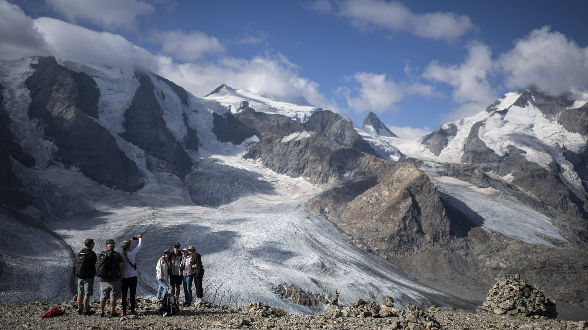 epa10113963 Tourists hike in front of the Bernina mountain group with the Pers and Morteratsch glaciers in Pontresina, Switzerland, 10 August 2022. The hot summer of 2022 is believed to set a new record in melting glaciers.  EPA/GIAN EHRENZELLER