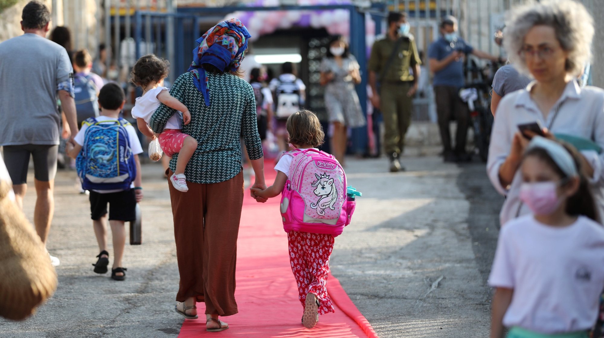 epa09439776 Children enter an elementary school on the first day of school in Jerusalem, Israel, 01 September 2021. Israel started a national quick Covid-19 testing campaign for kids aged 3 to 12 in order to safely reopen schools on September 01.  EPA/ABIR SULTAN