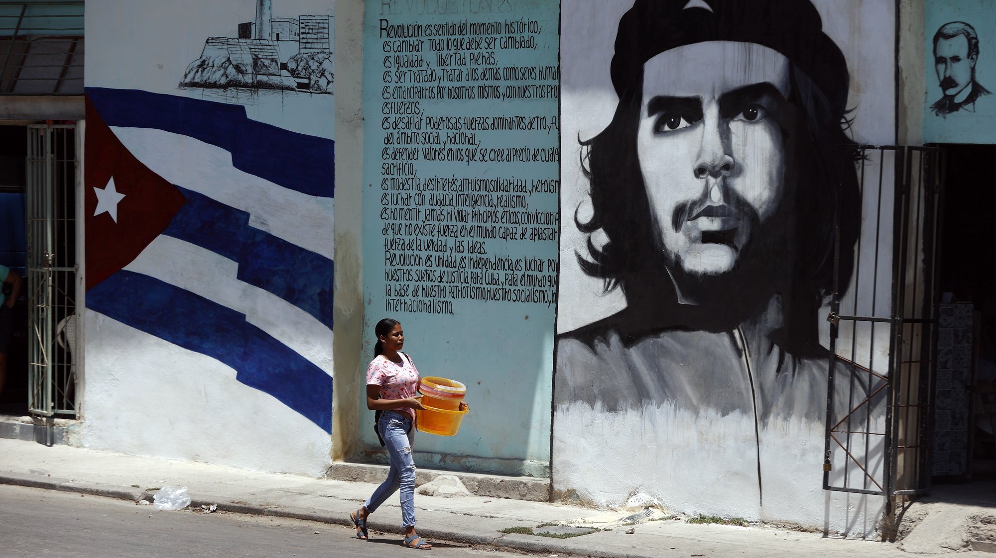epa11302962 A woman walks in front of a mural with the image of Argentine revolutionary Ernesto Che Guevara in the streets of Havana, Cuba, 26 April 2024.  EPA/Ernesto Mastrascusa