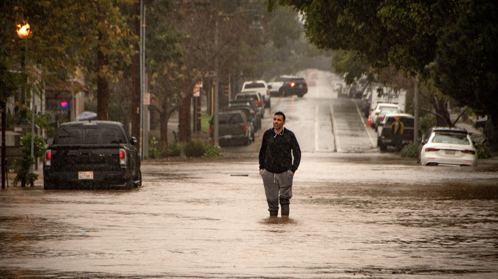 epaselect epa11127777 A man stands in the middle of flooded Bath Street during an atmospheric river weather event in Santa Barbara, California USA, 04 February 2024. The Weather Prediction Center has issued a rare Level 4 of 4 risk of excessive rainfall for the Santa Barbara area, with the storm also triggering flood watches for nearly 40 million people in the state of California.  EPA/ERICK MADRID