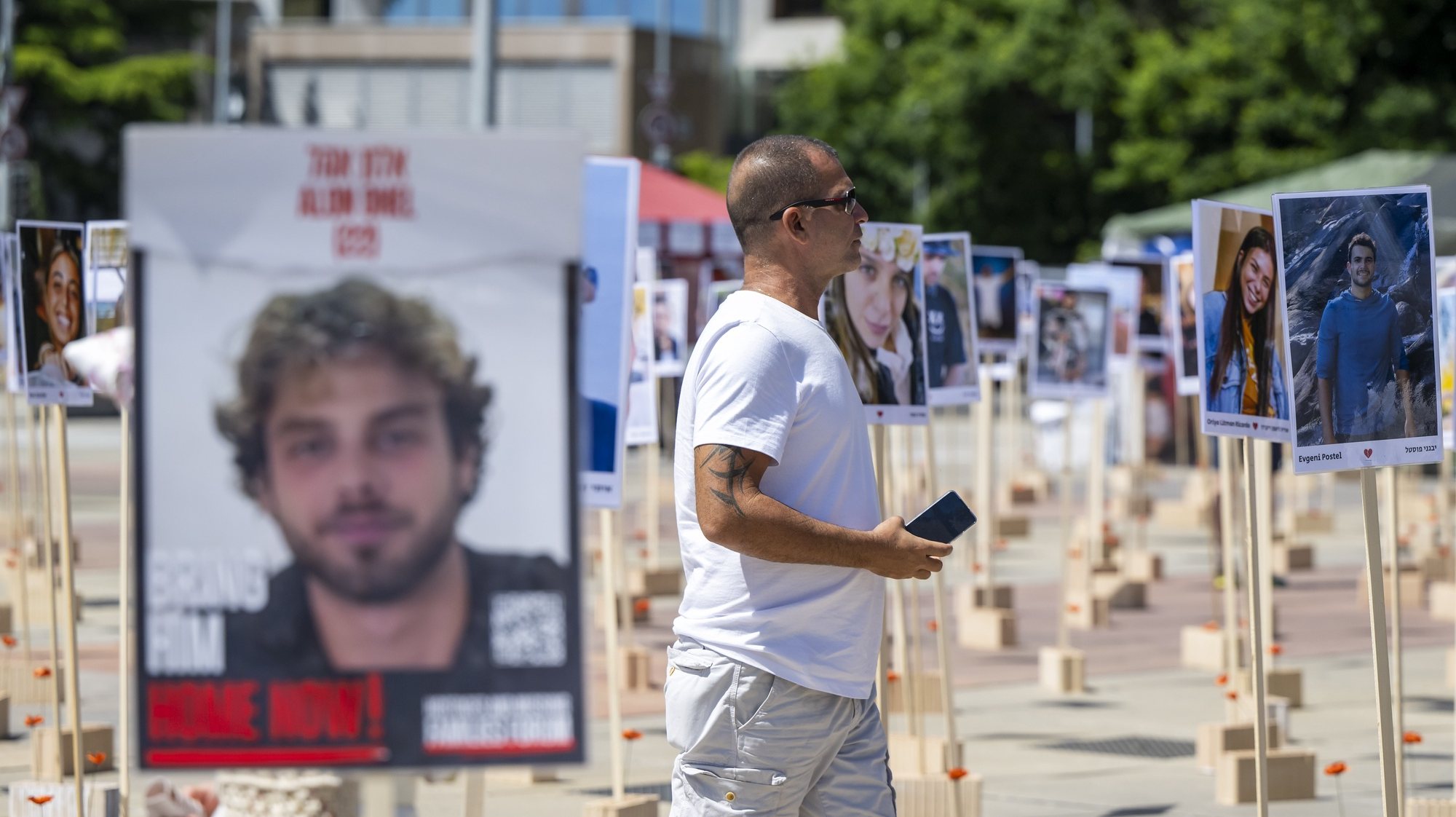 epa11422549 A person looks at portraits of Israeli hostages kidnapped by Hamas militants during the October 7 attacks that are installed in front of the United Nations European headquarters in Geneva, Switzerland, 19 June 2024, during the 56th session of the Human Rights Council.  EPA/MARTIAL TREZZINI