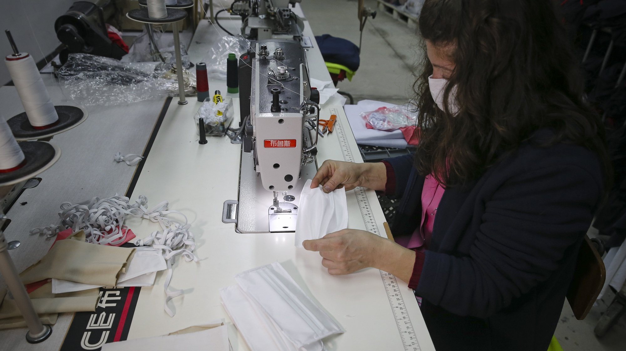 Funcionárias de uma empresa têxtil produzem máscaras descartáveis, em Barcelos, 21 de abril de 2020. Nesta altura, a Têxtilobo - The Textile Company, instalada na freguesia de Carapeços, está já certificada, pelo Centro Tecnológico das Indústrias Têxtil e do Vestuário de Portugal (CITEVE), para a produção de máscaras descartáveis. (ACOMPANHA TEXTO). JOSÉ COELHO/LUSA