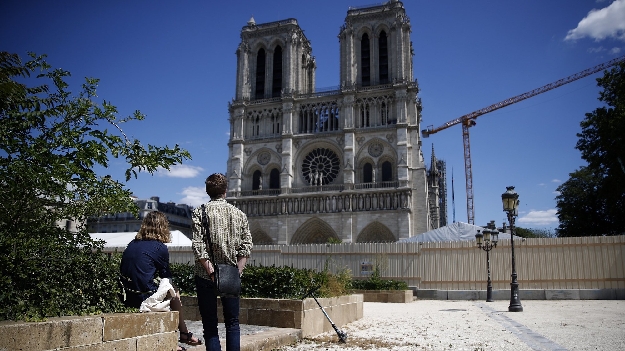 epa08456387 People stand in front of the Notre-Dame cathedral as the forecourt reopens to public in Paris, France, 31 May 2020. The forecourt of the cathedral was closed to public due to lead pollution after Notre-Dame Cathedral of Paris suffered a devastating fire on 15 April 2019.  EPA/YOAN VALAT