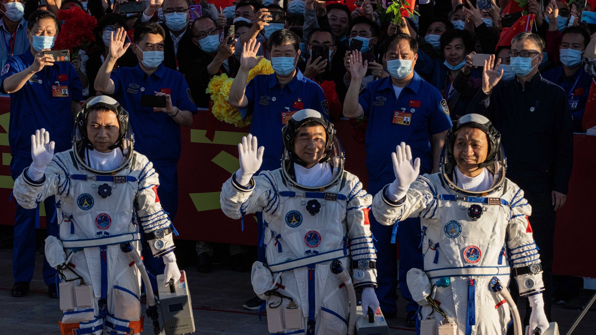 epa09278427 Chinese astronauts Tang Hongbo, Nie Haisheng, and Liu Boming wave during a departure ceremony before the launch of the Long March-2F carrier rocket, carrying the Shenzhou-12 at the Jiuquan Satellite Launch Center, in the Gobi Desert, northwest of China, 17 June 2021. China launches Shenzhou-12 spacecraft carrying three crew members Tang Hongbo, Nie Haisheng, and Liu Boming to the orbiting Tianhe core module for a three-month mission on 17 June. It is the first spaceflight in almost five years where China sends humans into space.  EPA/ROMAN PILIPEY