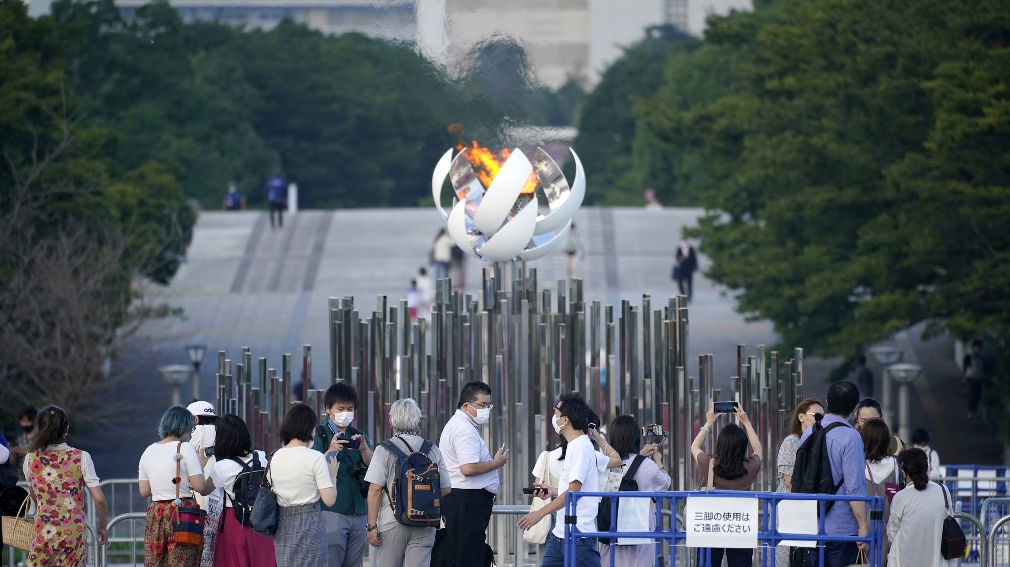 epa09373419 People take photos of the Olympic Flame in Tokyo, Japan, 28 July 2021. The Japanese capital recorded 3,177 new coronavirus cases on 28 July, hitting a new daily record for the second day in a row. It reported 2,848 cases on 27 July, adding further pressure on the country&#039;s health care system.  EPA/FRANCK ROBICHON