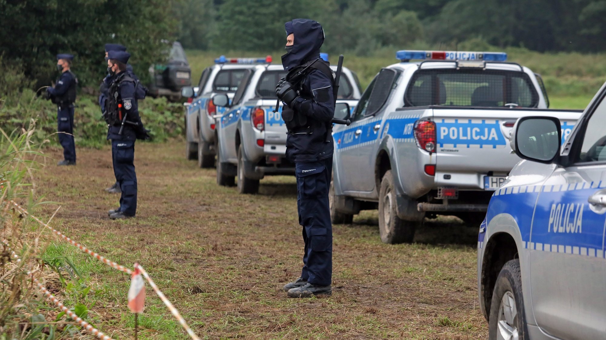 epa09436765 Polish police officers stand at the Polish-Belarusian border near Usnarz Gorny village, north-west Poland, 30 August 2021. The number of migrants from Iraq, Syria, Afghanistan and other countries trying to cross the Belarusian border into neighbouring EU states has increased sharply in recent months. According to official sources, a group of 24 people, including 20 men and four women but no children, camped at Usnarz Gorny on the Belarusian side of the Polish-Belarusian border.  EPA/ARTUR RESZKO POLAND OUT