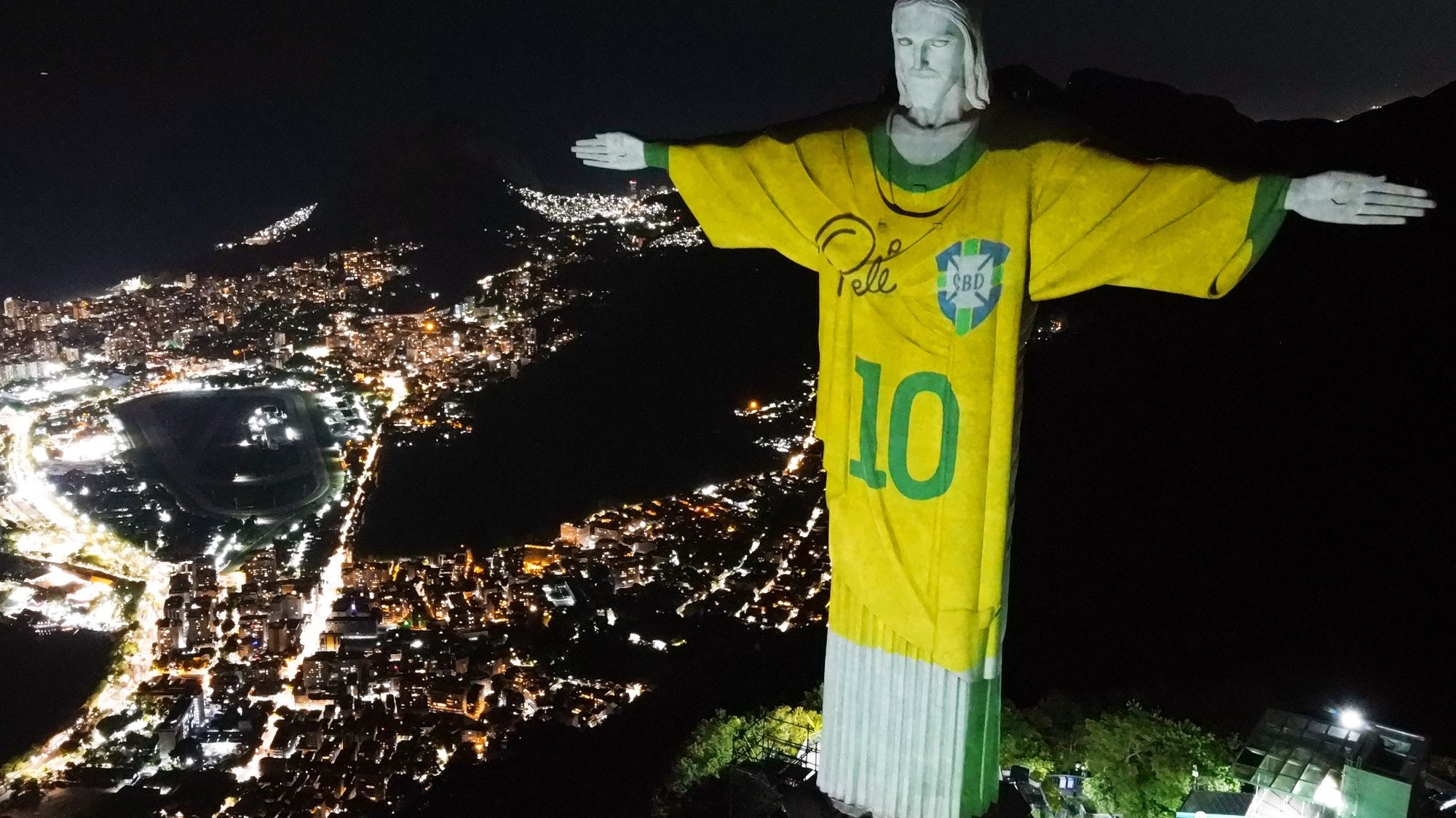 epaselect epa11048883 An aerial view of Christ the Redeemer statue illuminated with a projection of the Brazilian soccer team jersey worn by Pele, in Rio de Janeiro, Brazil, 29 December 2023. The projection is part of tributes throughout Brazil amid the first anniversary of the death of the &#039;King of Soccer&#039;.  EPA/ANDRE COELHO
