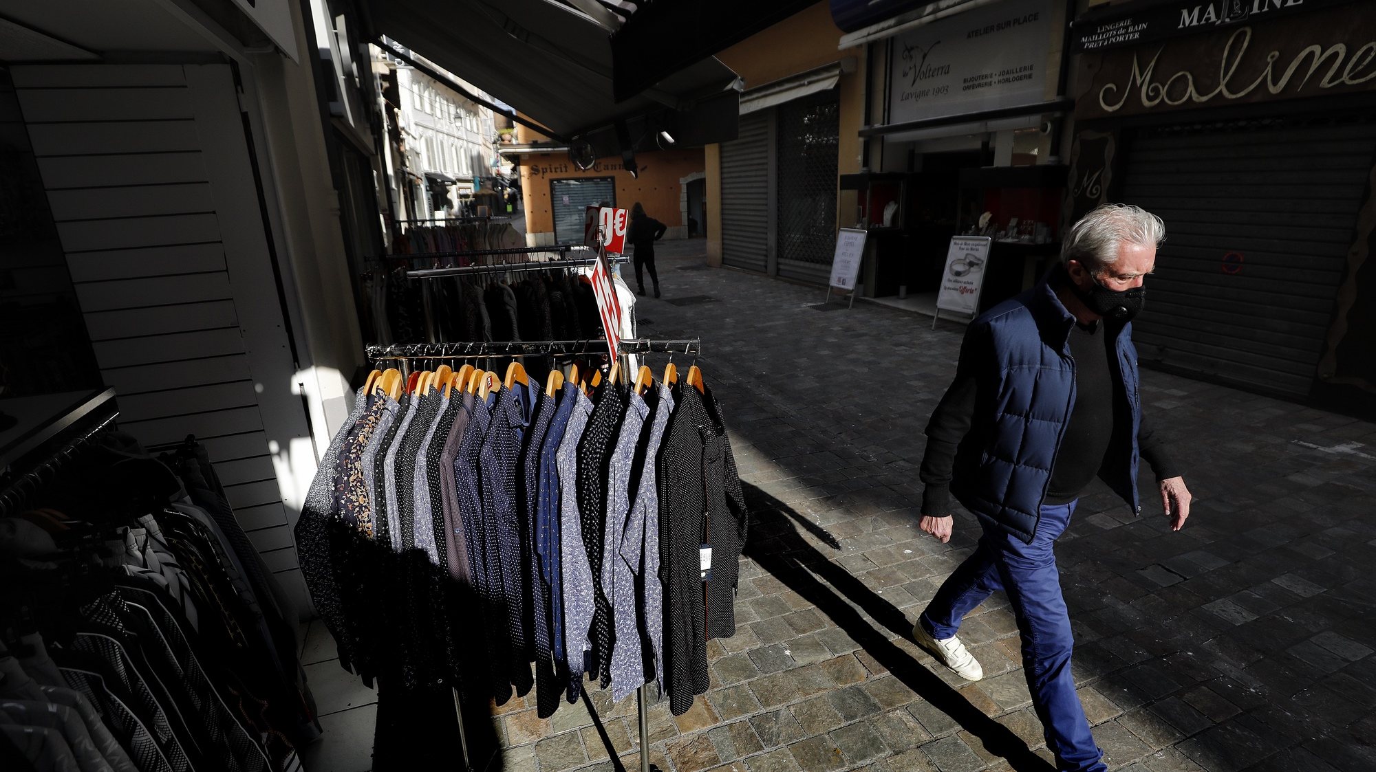 epa09097124 A man walks past a clothing store that displays these clothes on the streets during the lockdown in Cannes, France, 25 March 2021. New COVID-19 lockdown restrictions include the closure of &#039;non-essential&#039; businesses, but the town halls of Cannes, Antibes, and Menton allow the sale of non-essential outdoor businesses.  EPA/SEBASTIEN NOGIER