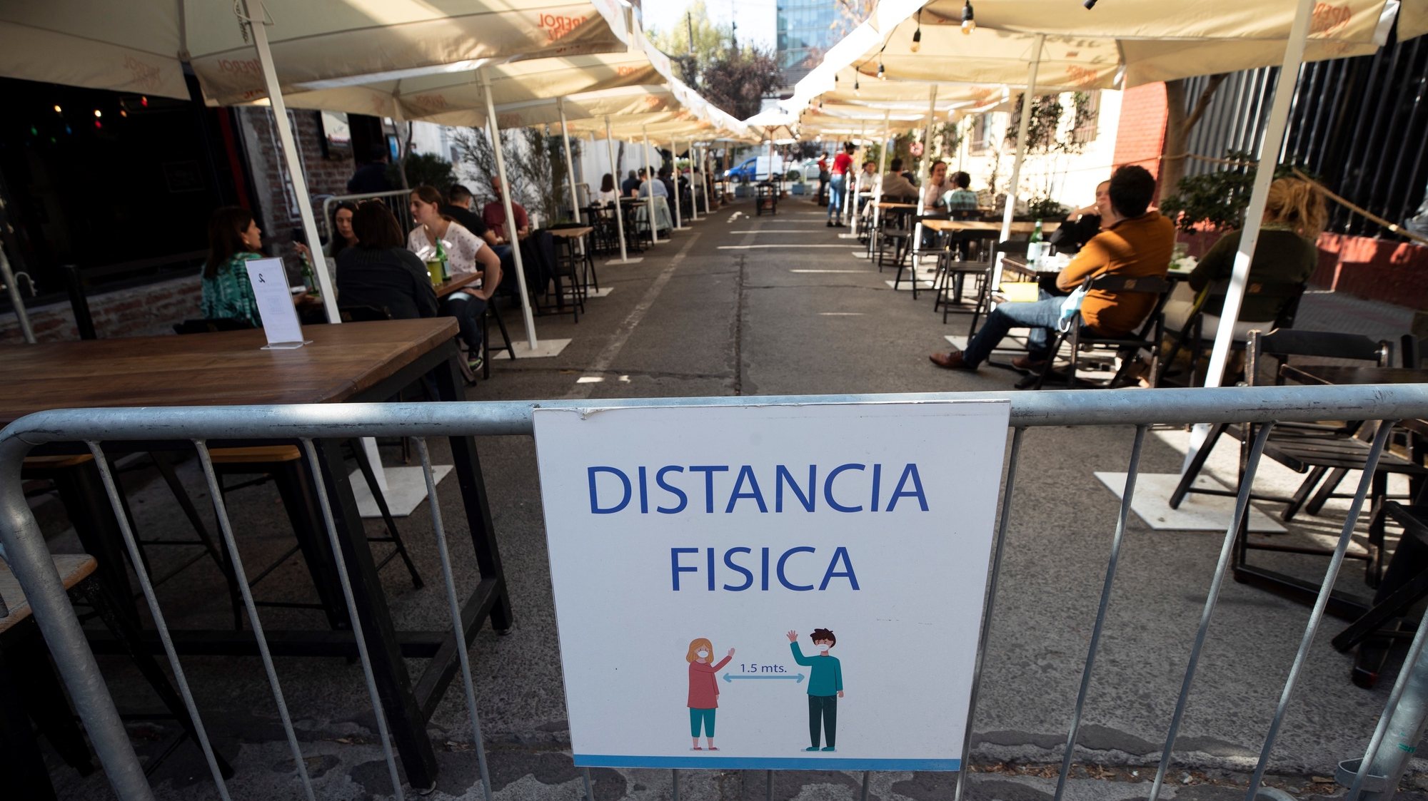 epa09168596 View of a notice of physical distancing on a terrace where a group of people enjoy lunch  in Santiago, Chile 29 April 2021. With the hangover of having been in total quarantine for more than a month, Chileans from several capital neighborhoods returned to the streets this 29 April with a view to leaving behind a harsh second wave of the pandemic, which worsened in March, and with their hopes pinned in the rapid vaccination process.  EPA/Alberto Valdes