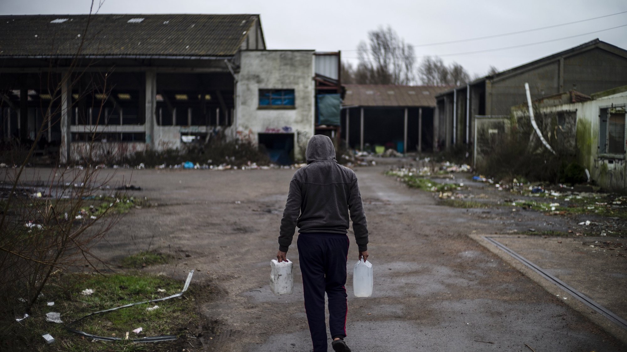 epa08179161 A refugee carries water inside the makeshift migrant camp in Grande-Synthe, near Dunkerque, France, 30 January 2020. The camp in Grande-Synthe counts an estimated 500 residents mostly composed of Kurds from Iraq. They are still hoping to reach United Kingdom even if Britain is due to leave the European Union on 31 January 2020.  EPA/YOAN VALAT