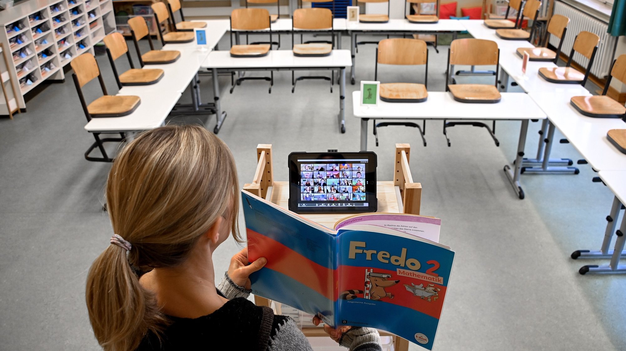 epaselect epa08947400 A teacher stands in an empty classroom and uses an iPad to teach children at home, at the closed elementary school ‘Am Weyer’ in Dinslaken, Germany, 18 January 2021. To slow the spread of the coronavirus, schools in Germany remain closed. All students must study from home during the nationwide lockdown. The heads of the German states will meet with German Chancellor Angela Merkel on 19 January 2021, to discuss how to proceed in the corona crisis. The current lockdown is to be extended beyond 31 January 2021. A complete shutdown in Germany and an actual curfew are also being discussed.  EPA/SASCHA STEINBACH