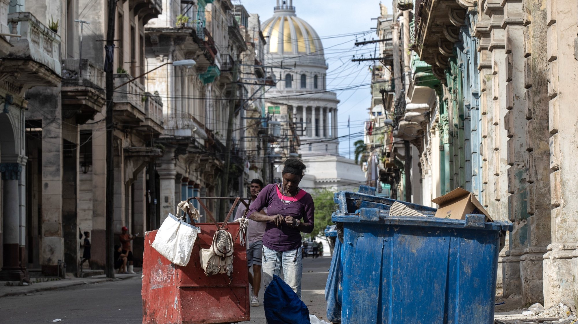 epa11076696 A woman searches through a garbage container a block away from the National Capitol Building in Havana, Cuba, 11 January 2024 (issued 14 January 2024). Divers, locally known as ‘buzos’, searching through garbage tanks are an increasingly common sight in Havana and other Cuban cities, where three years of serious economic crisis are taking a dramatic social toll.  EPA/YANDER ZAMORA