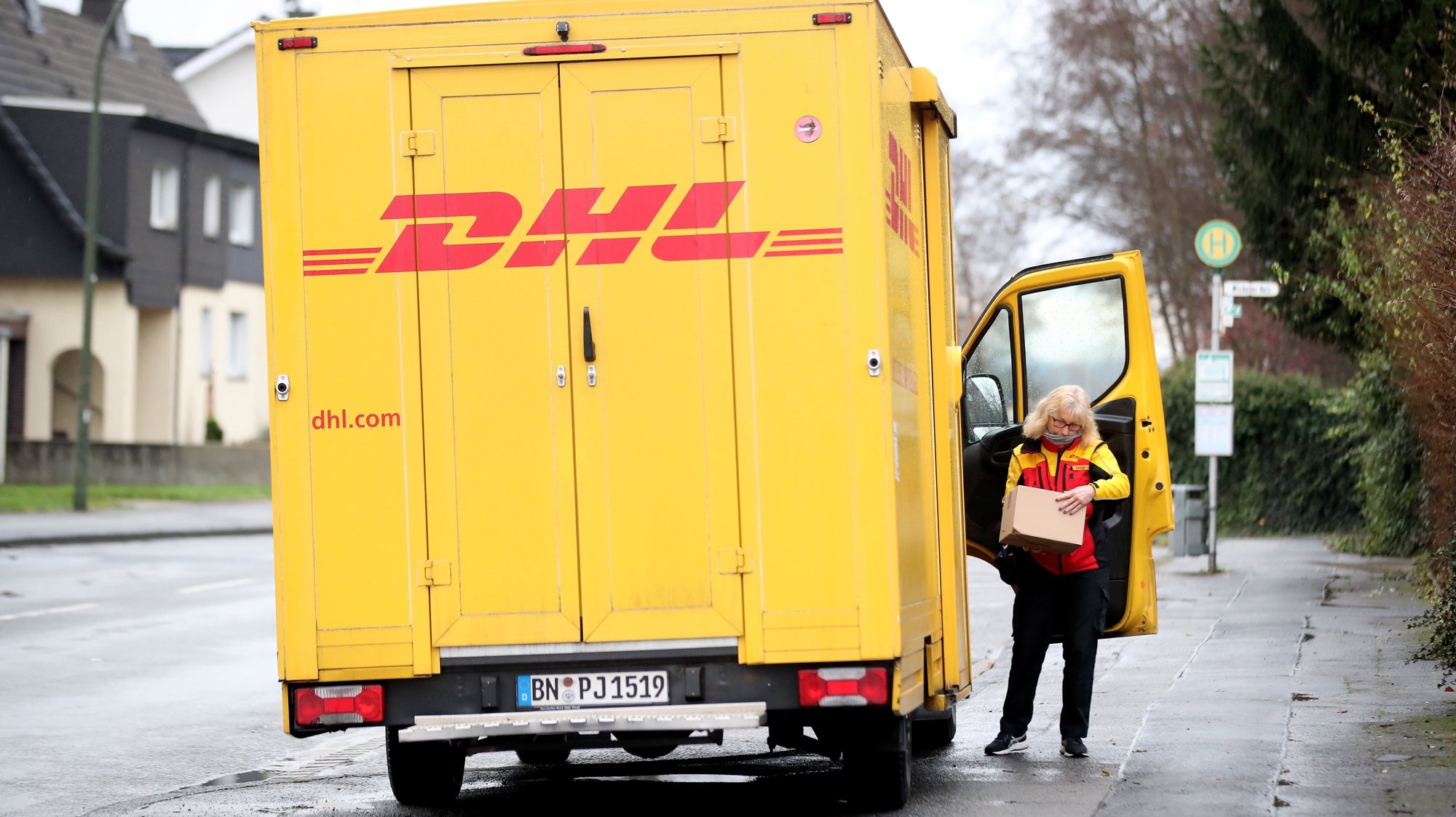 epa08885604 A parcel carrier of the Deutsche Post DHL Group logistics and postal services company delivers parcels in a residential area in Dortmund, Germany, 15 December 2020. According to a company spokesman, Deutsche Post DHL Group expects to break the record of 11 million parcel shipments per day several times in the run-up to Christmas.  EPA/FRIEDEMANN VOGEL
