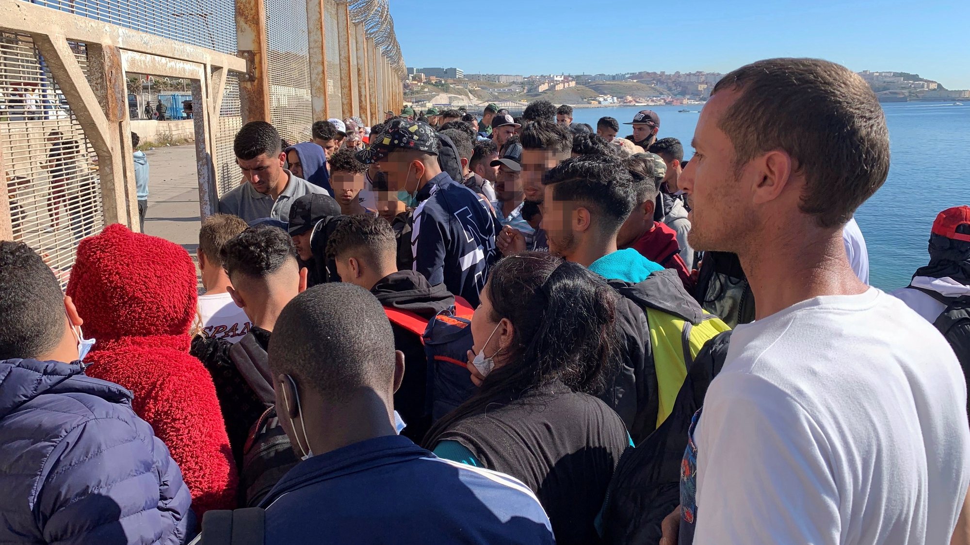 epa09211167 A group of people try to cross the border fence separating Fnideq (Castillejos, Morocco) and the Spanish city of Ceuta, located in northern Africa, 19 May 2021, following the arrival of up to 8,000 migrants to Ceuta and the Spanish city of Melilla (also in northern Africa) in the last two days. Spain&#039;s Government considers that the massive arrival of some 8,000 irregular migrants to Ceuta from Morocco since 18 May is an assault on the border caused by the lack of control of the border by Morocco&#039;s Governmet and not a migratory crisis.  EPA/Mohamed Siali