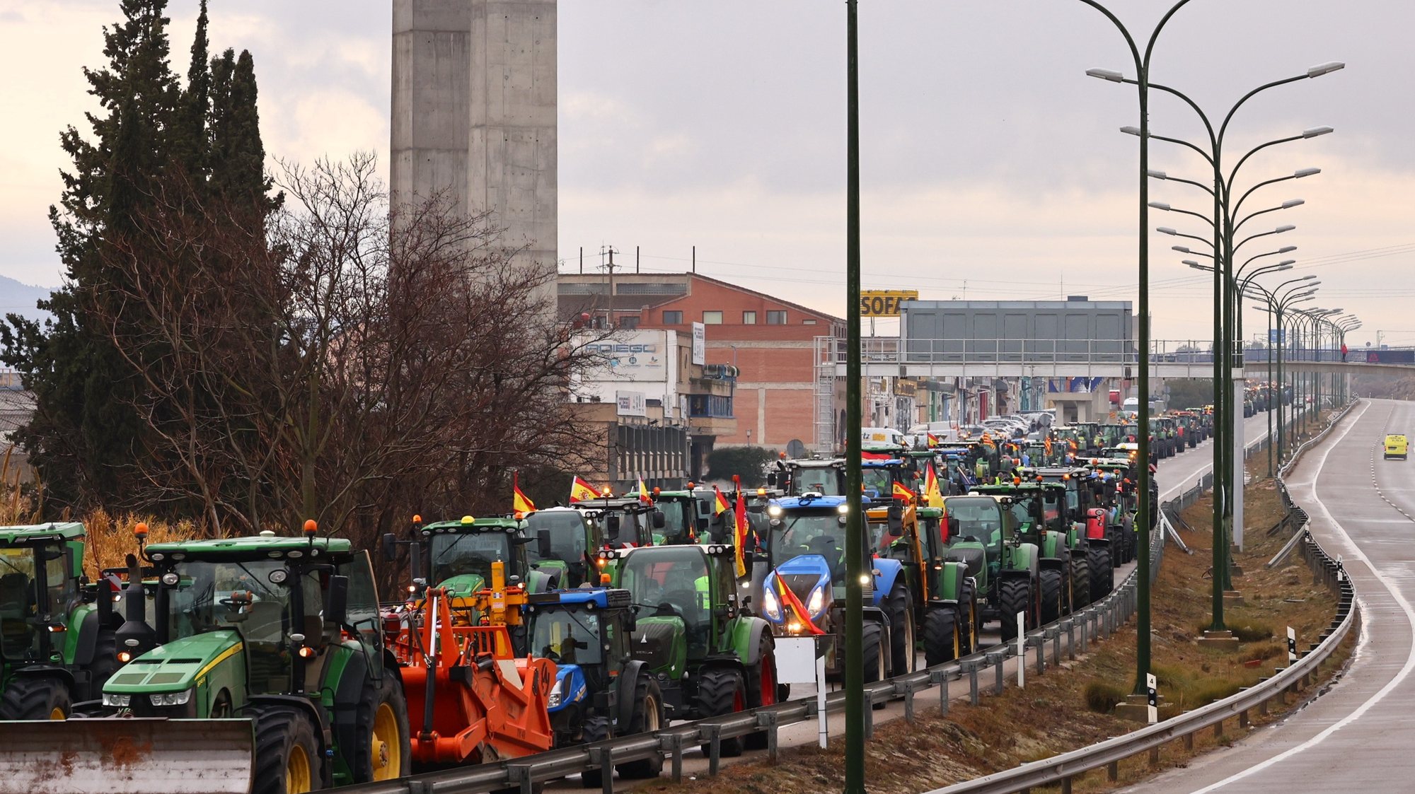 epa11139054 Farmers block a road with tractors on the fourth consecutive day of protests in Zaragoza, Spain, 09 February 2024. Farmers protest against green measures planned by the European Union, calling for fairer trade agreements and aid to deal with climate crises such as drought.  EPA/TONI GALAN