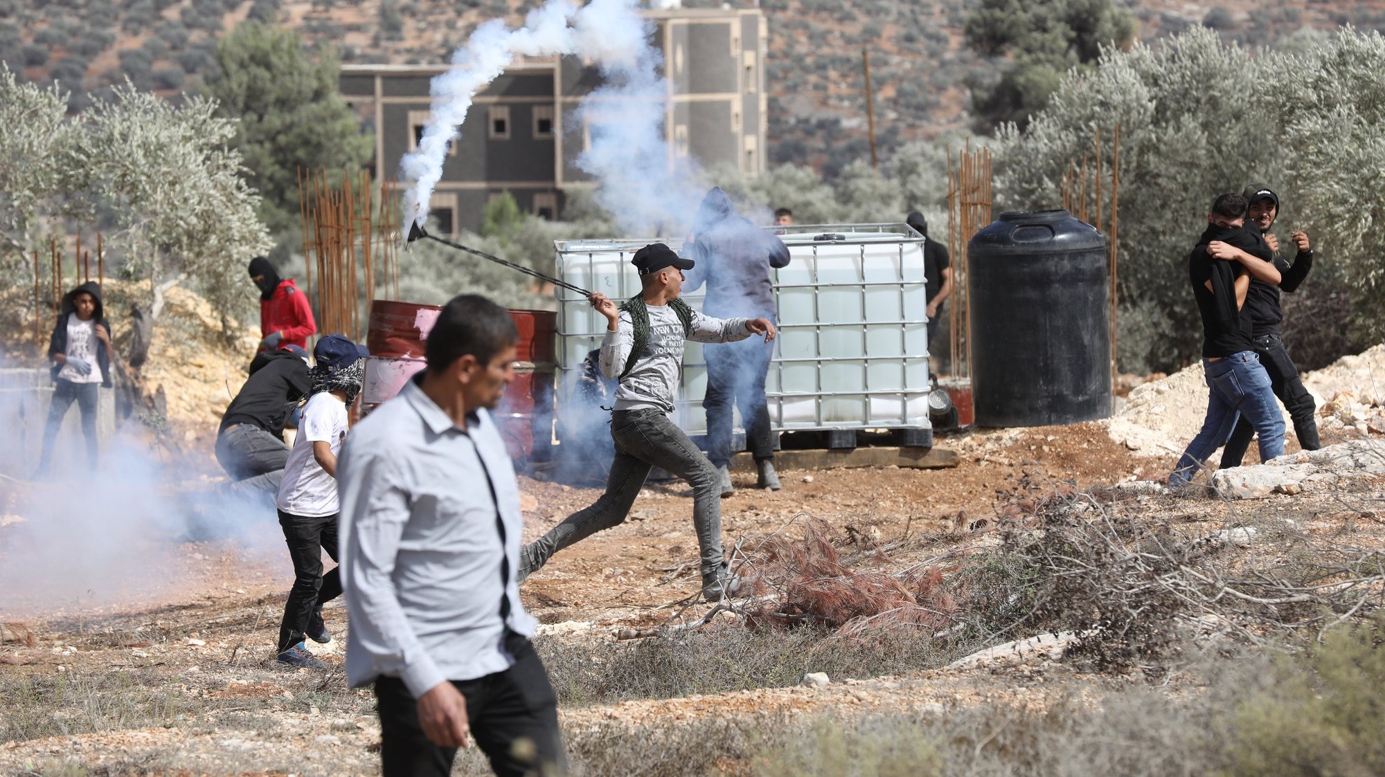 epa09485731 A Palestinian protestor throws back a tear gas grenade during clashes with Israeli security forces after a protest against Israeli settlements, on the lands of Beita village near the West Bank city of Nablus, 24 September 2021.  EPA/ALAA BADARNEH