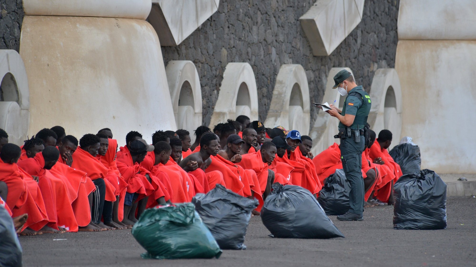 epa10928742 An officer checks 148 sub-Saharan immigrants that include 20 minors and eight women, after arriving at the port of La Restinga, El Hierro, Canary Island, Spain, 20 October 2023.  EPA/Gelmert Finol