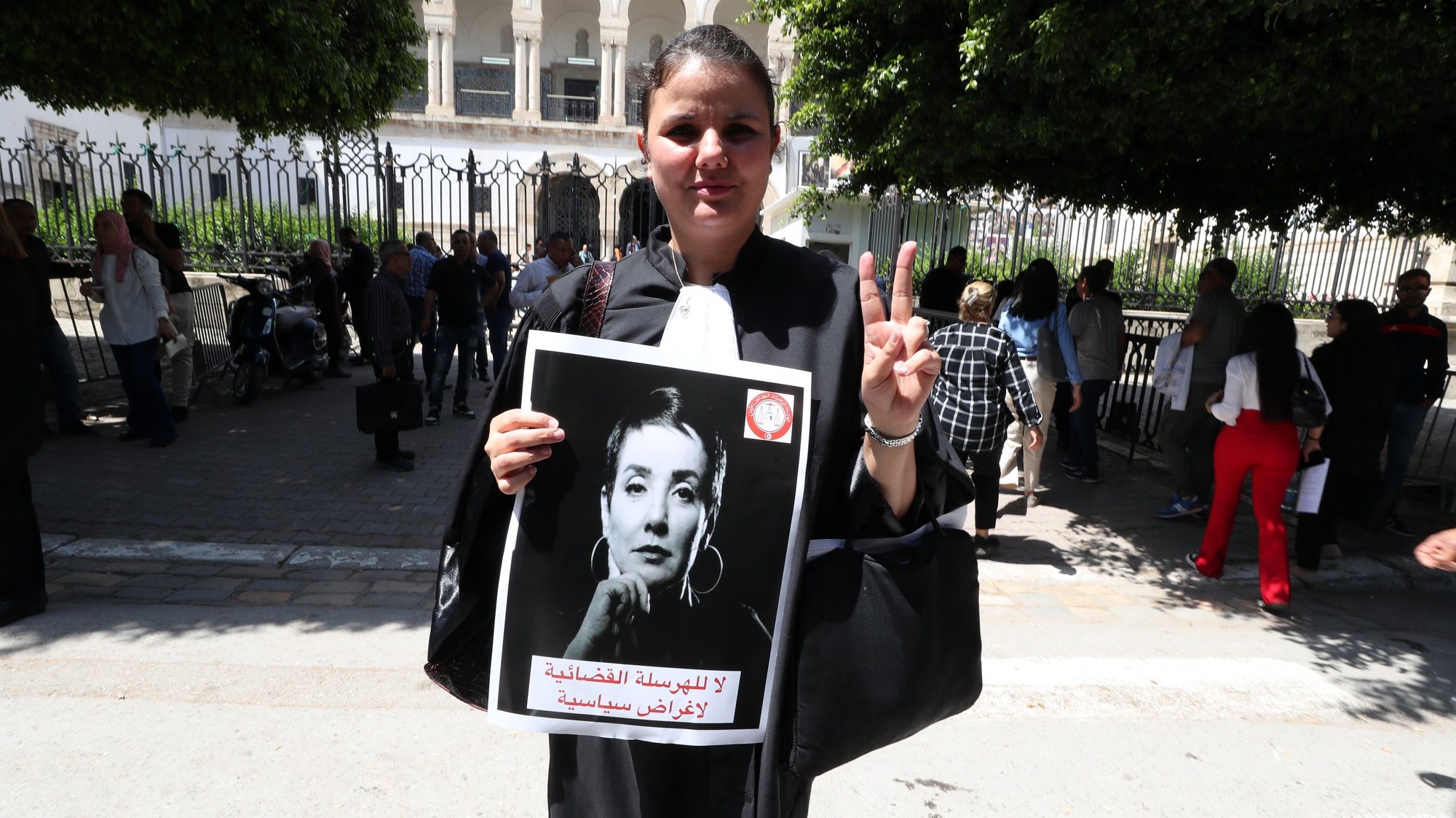 epa11337021 A lawyer carries a photo of Sonia Dahmani, a lawyer critical of the president, during a rally in front the Palace of Justice building in Tunis, Tunisia, 13 May 2024. The council of the National Order of Tunisian Lawyers has decided on a general strike of lawyers and a boycott of hearings to protest against the assault of the police on its premises to carry out the arrest on 11 May  of two commentators politicians including lawyer Sonia Dahmani, following critical comments on the Carthage+ channel.  EPA/MOHAMED MESSARA