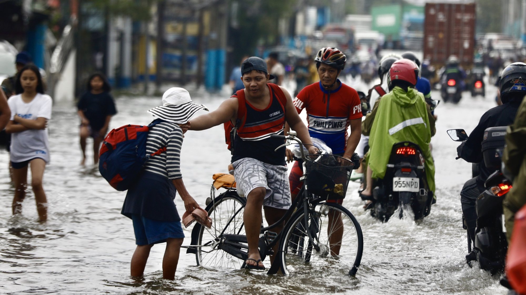epa11495532 Pedestrians and motorists make their way through the water on a flooded road in Meycauayan, Bulacan, Philippines, 25 July 2024. A state of calamity was declared in the Philippine capital of Metro Manila and neighboring provinces in order to activate resources to address the effects of massive floods from monsoon rainfalls caused by typhoon Gaemi on 24 July. Flood evacuees began returning to their homes while other affected families still remain in evacuation centers in need of relief supplies.  EPA/FRANCIS R. MALASIG