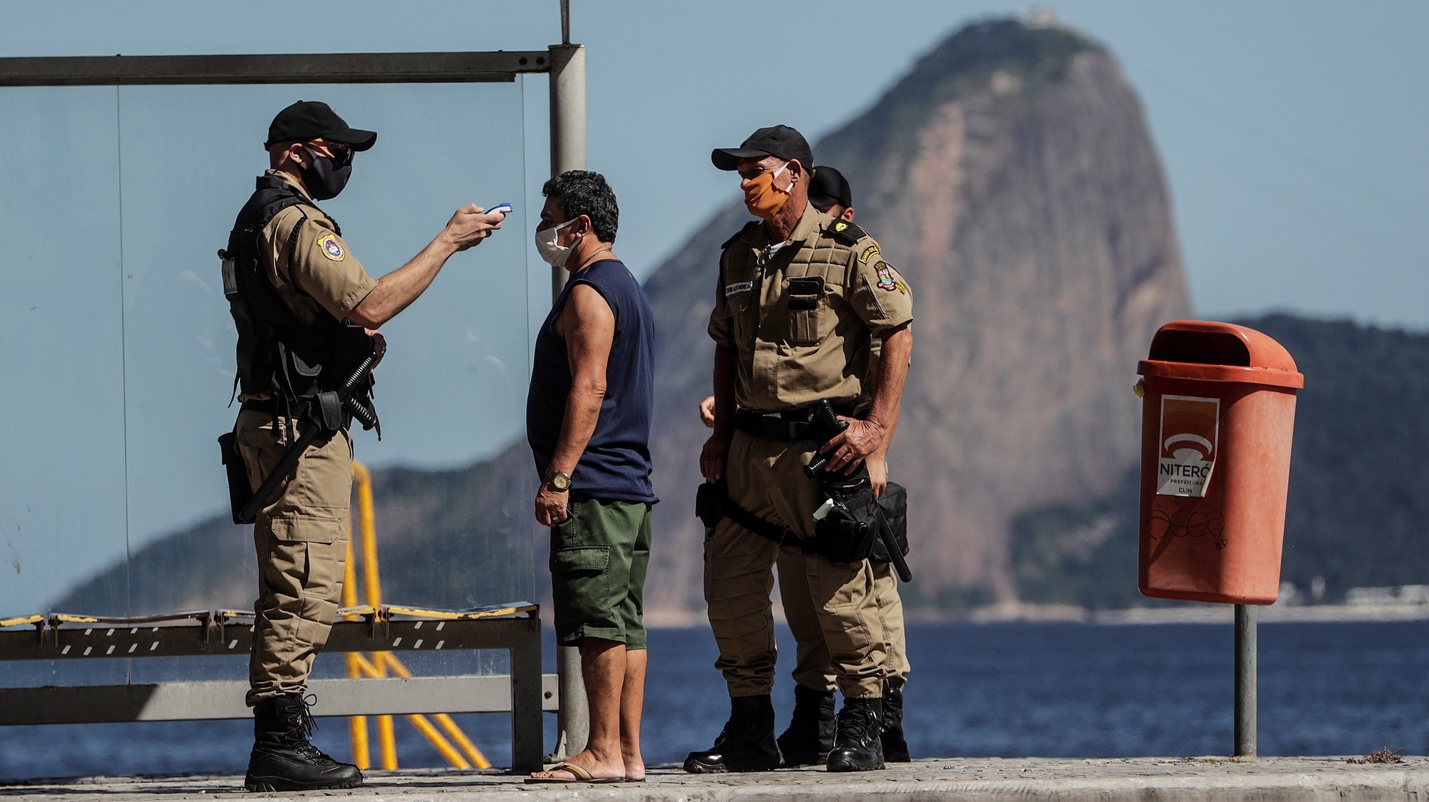 epa08415591 A security officer from the Niterioi city council takes a man&#039;s temperature in Niteroi, Rio de Janeiro, Brazil, 11 May 2020. Cities of Niteroi and Sao GonÃ§alo became the first municipalities in the state of Rio de Janeiro to intensify the restrictive measures of traffic and circulation of people by decreeing the so-called &#039;lockdown&#039;, which will be applied for an initial period of five days. With these two municipalities in the metropolitan region of Rio de Janeiro, there are already twenty Brazilian cities adopting a total blockade to prevent the spread of the pandemic.  EPA/Antonio Lacerda