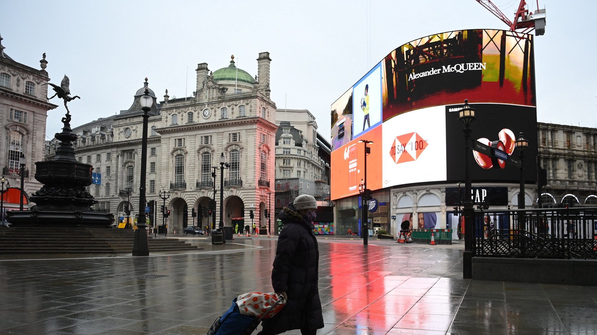 epa08920047 A masked woman passes a quiet Piccadilly Circus in London, Britain, 05 January 2021. British Prime Minister Boris Johnson announced on 04 January evening that there would be a third national lockdown in England. The regulations, expected to remain in place until the middle of February, will be presented in parliament on 05 January and subject to a vote on 06 January 2021.  EPA/NEIL HALL