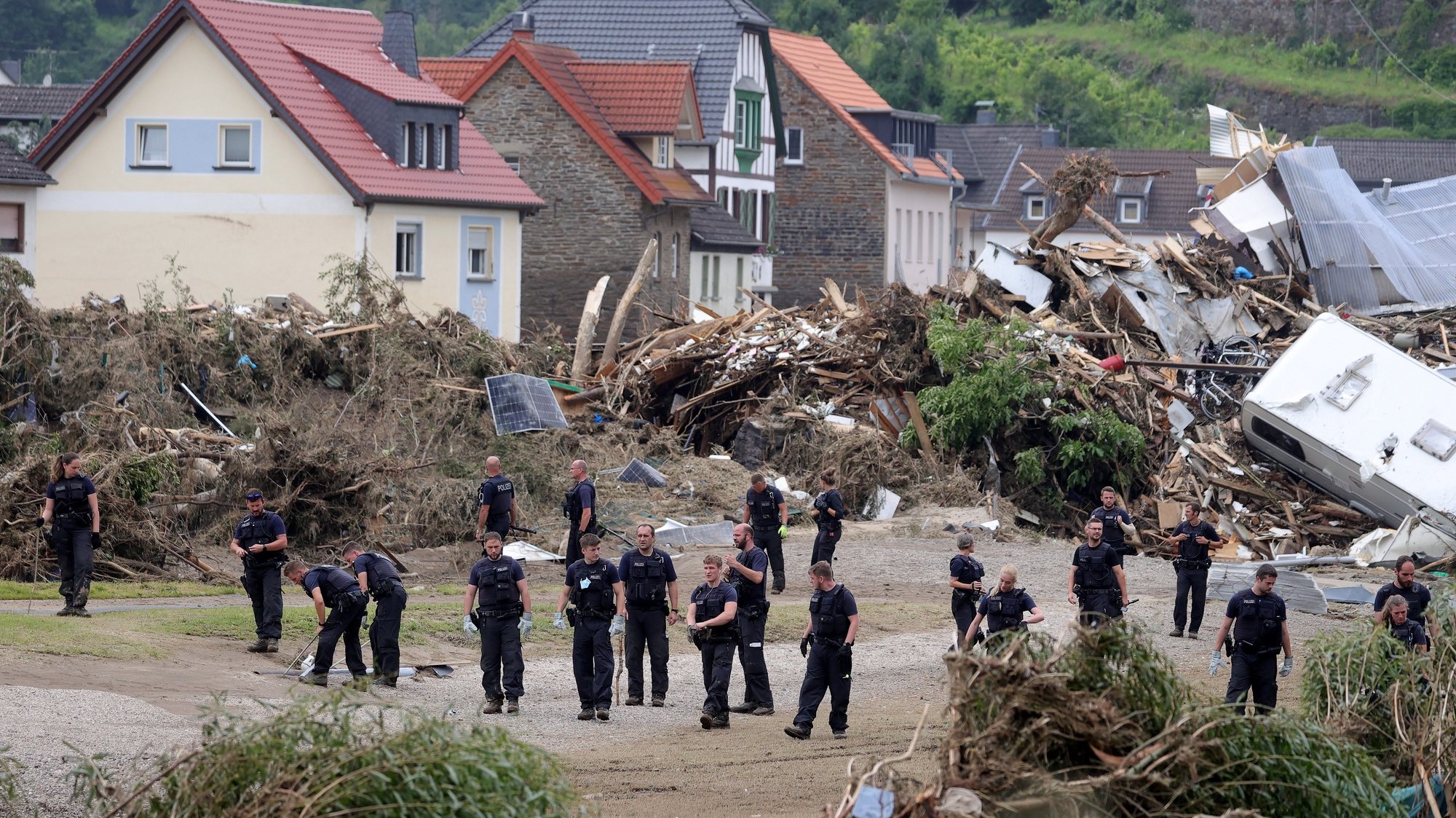 epa09353802 Police officers inspect the area after the flooding of the Ahr River, in Altenahr, Germany, 19 July 2021. Large parts of western Germany and central Europe were hit by flash floods in the night of 14 to 15 July, following days of continuous rain that destroyed buildings and swept away cars. The total number of victims in the flood disaster in western Germany rises to at least 164, with many hundreds still missing.  EPA/FRIEDEMANN VOGEL