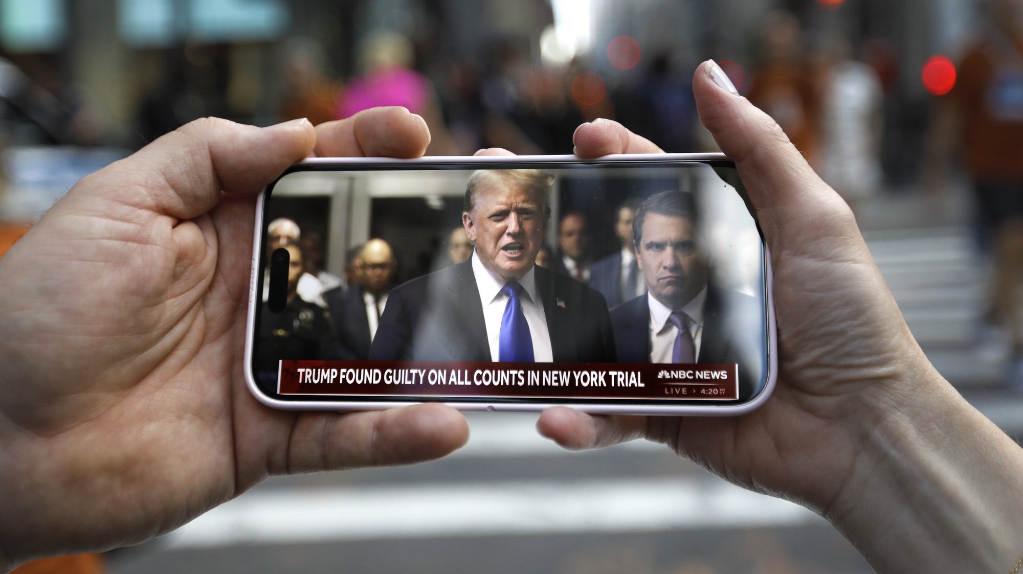epa11380833 Two people watch Former US President Donald Trump at criminal court speak on their mobile phone outside Trump Tower after a jury found former US President Donald Trump guilty on all 34 counts in his criminal trial in New York State Supreme Court in New York, New York, USA, 30 May 2024. Trump was found guilty on all 34 felony counts of falsifying business records related to payments made to adult film star Stormy Daniels during his 2016 presidential campaign.  EPA/PETER FOLEY