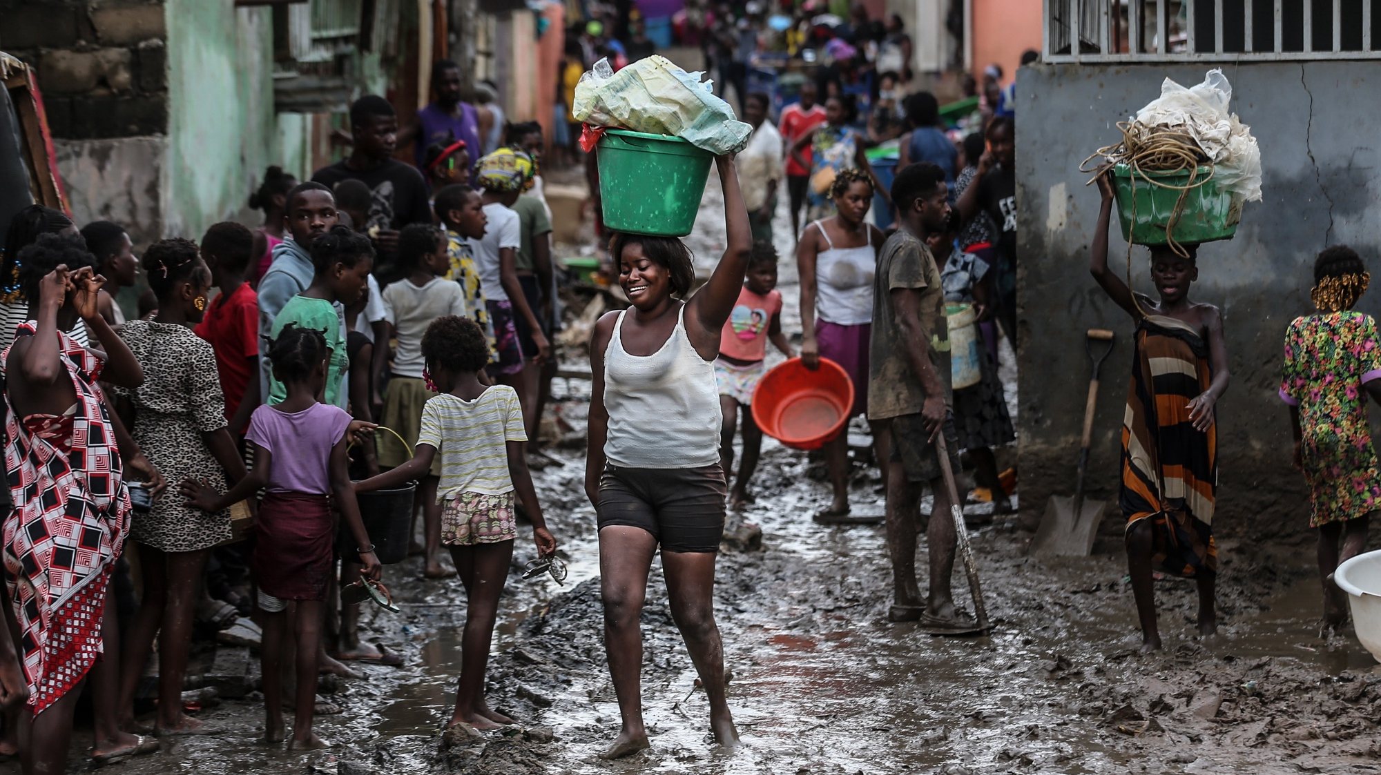 epa09147984 People on a muddy street after heavy rain that fell Monday night in Encide neighborhood, in the Sambizanga district, on the outskirts of Luanda, Angola, 20 April 2021. The torrential rains that hit Luanda on 19 April killed 14 people and left 8,000 displaced, with 16 houses collapsed, 15 trees fell, and a bridge was destroyed, among other damages yet to be calculated.  EPA/AMPE ROGERIO
