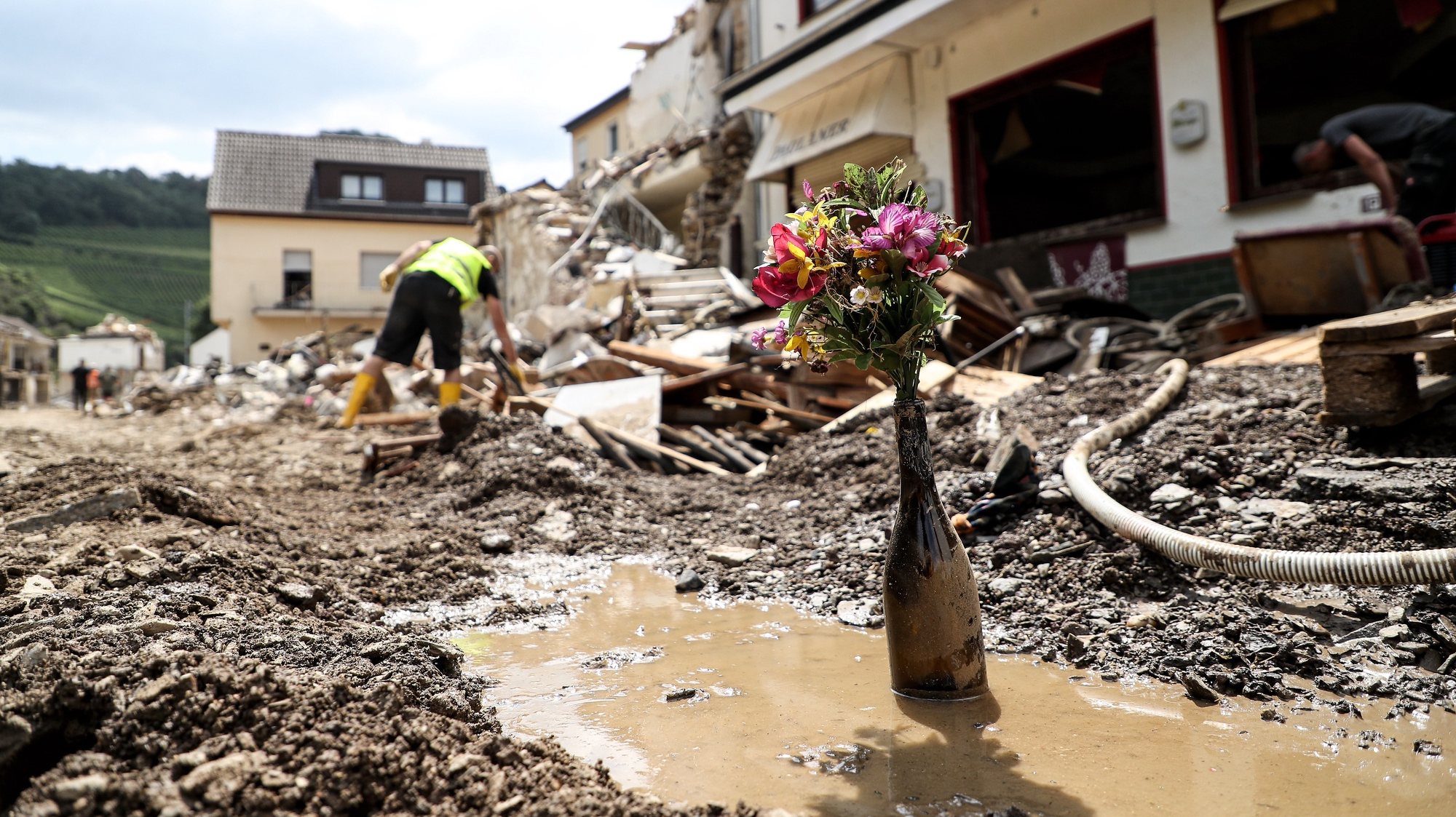epaselect epa09358245 Flowers in a wine bottle standing in front of a destroyed house after the flooding of the Ahr River, in Mayschoss in the district of Ahrweiler, Germany, 22 July 2021. Large parts of Western Germany were hit by heavy, continuous rain in the night to 15 July resulting in local flash floods that destroyed buildings and swept away cars.  EPA/FRIEDEMANN VOGEL